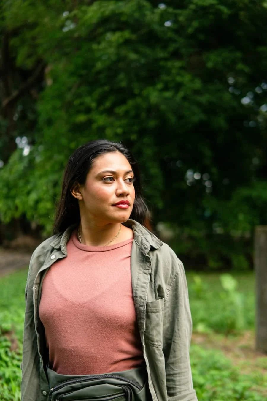 Woman standing outdoors in nature looking thoughtfully into the distance, representing self-reflection and reconnecting with personal needs.
