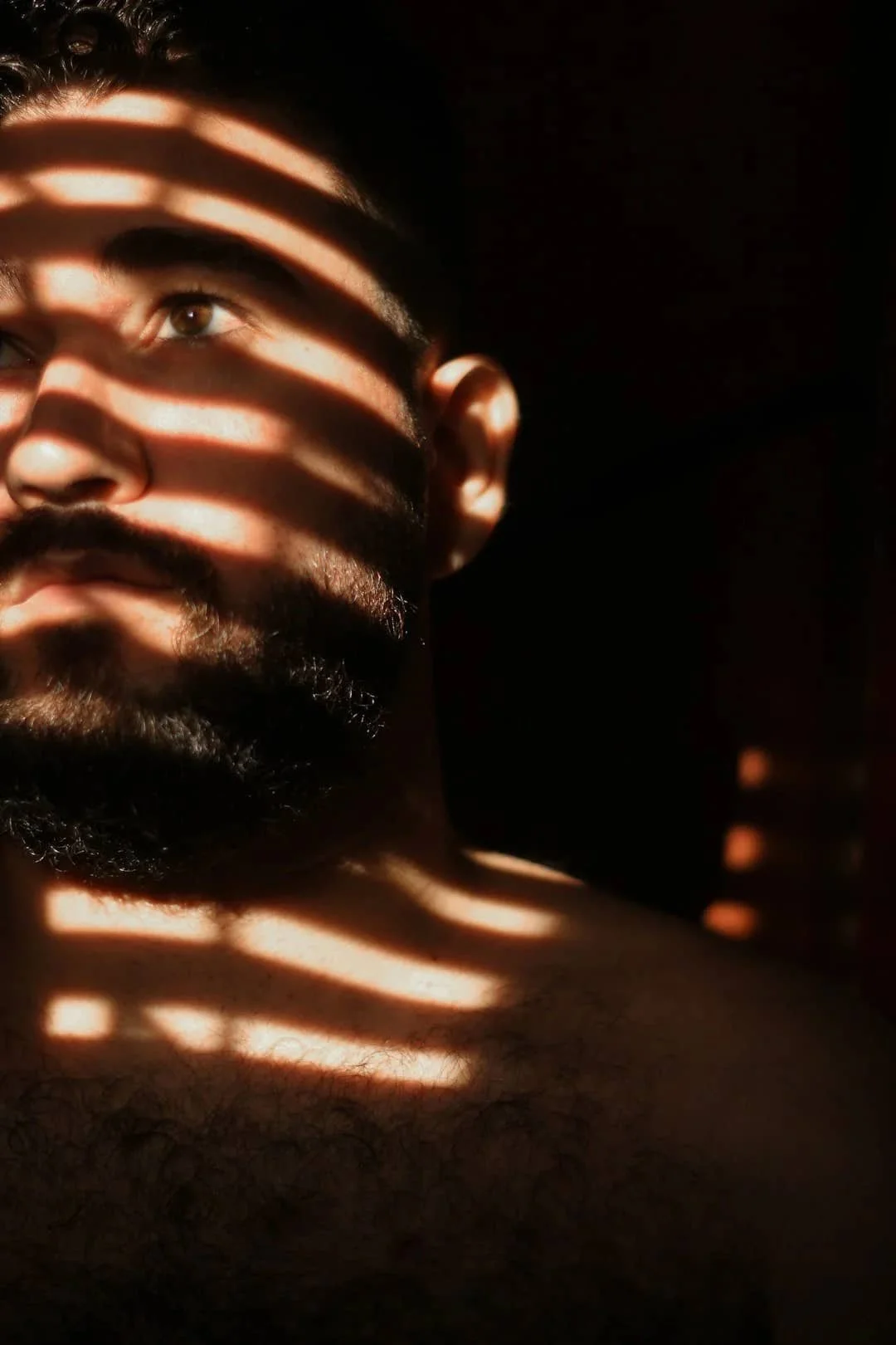 Thoughtful man with light and shadow across his face, reflecting the uncertainty of anxiety and intuition.