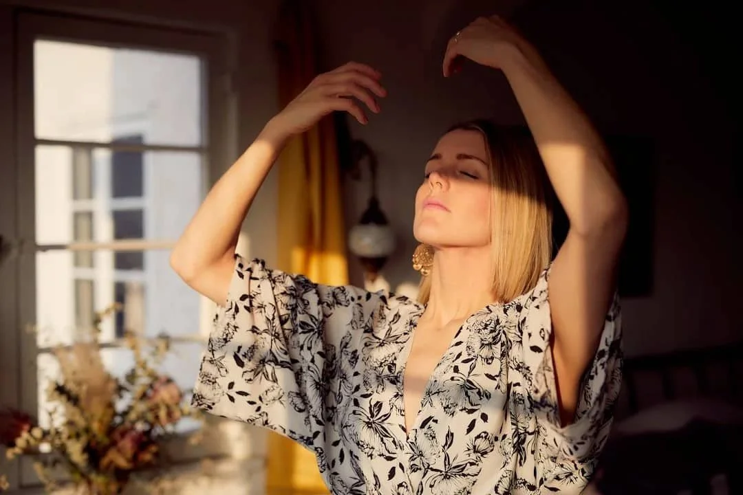 Woman pausing with her eyes closed, representing awareness of anxiety and nervous system signals in the body.