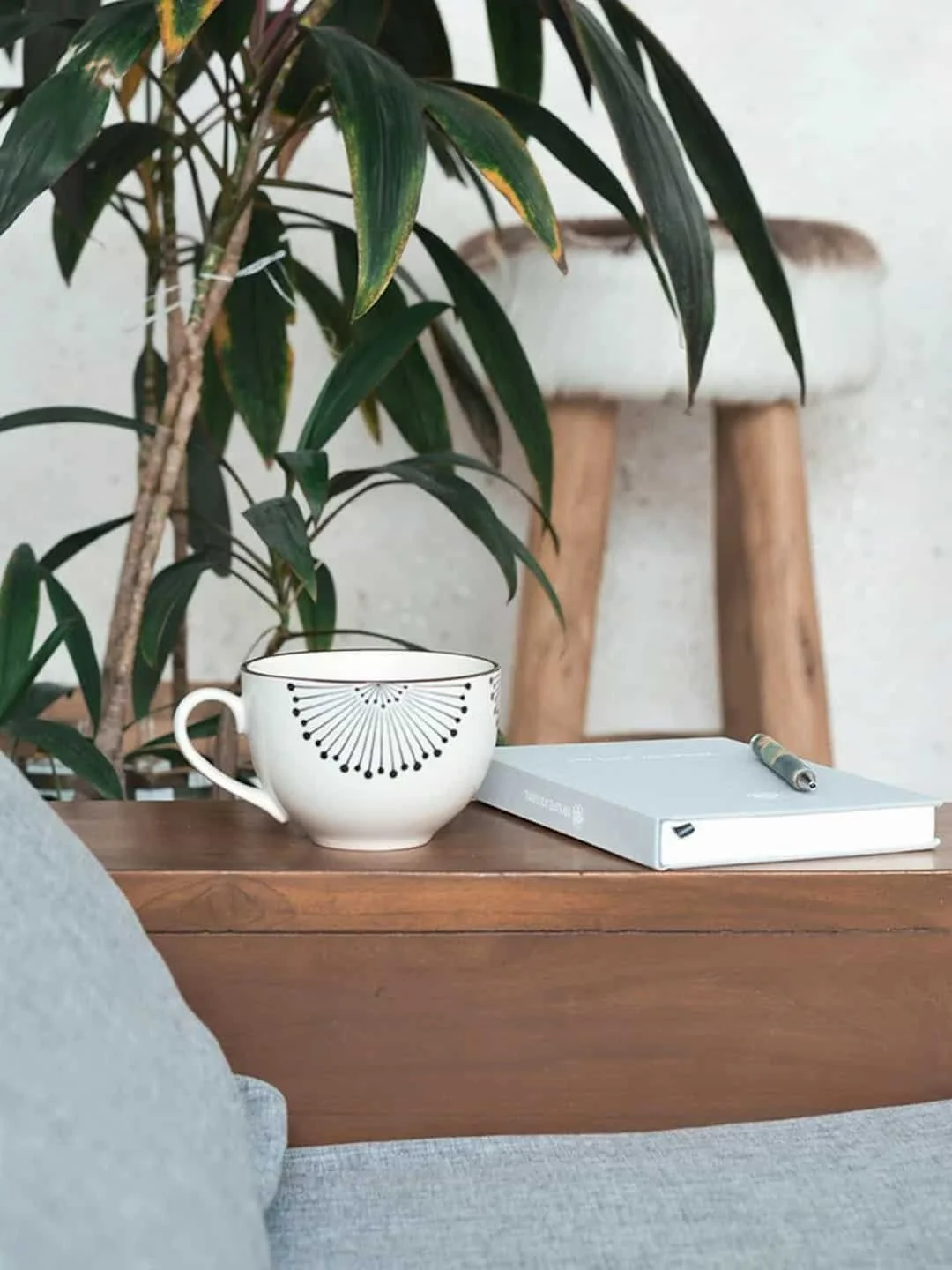 Journal, pen, and cup beside a comfortable chair.