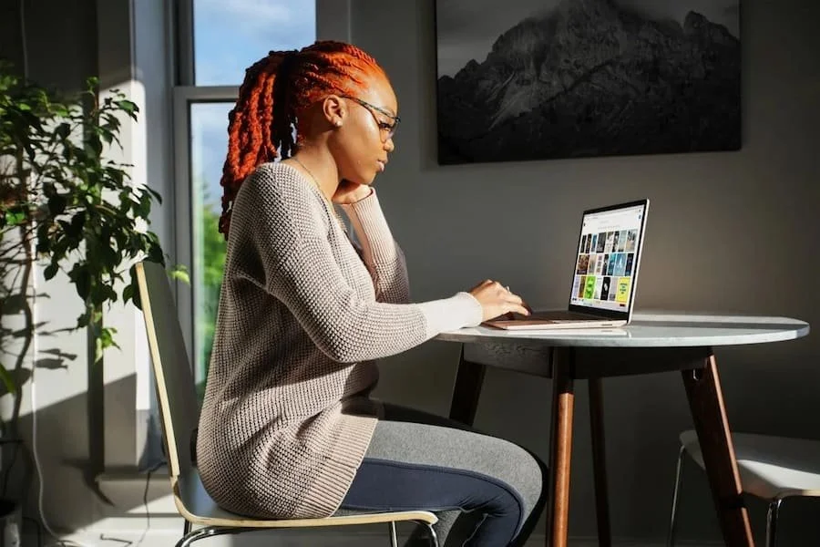 Woman sitting at a table working on a laptop at home.