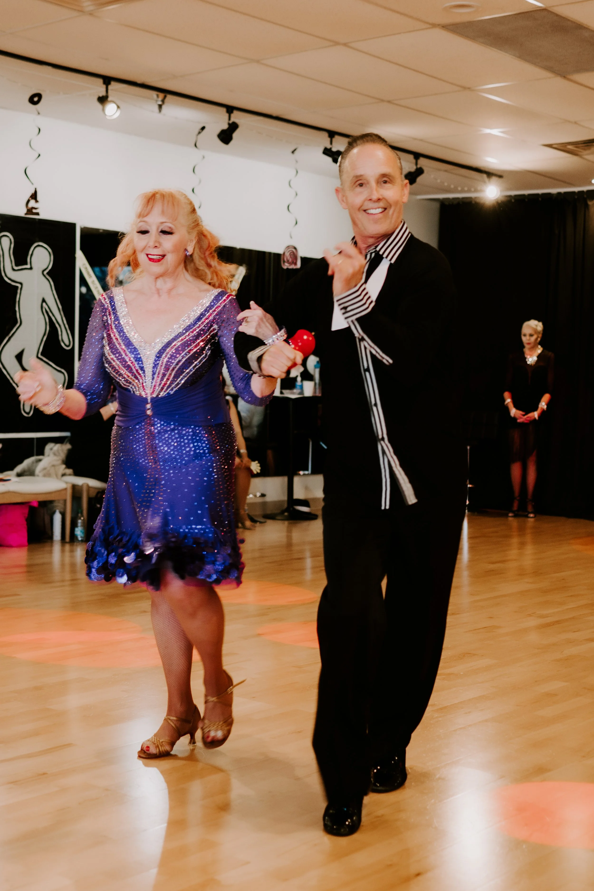 Three young adults socializing indoors, two women and one man, smiling and engaging in conversation amid hanging lights and festive decorations.