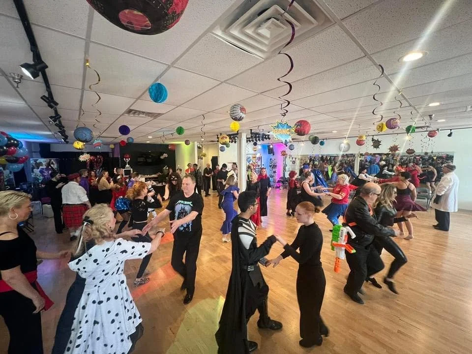 People dancing in a decorated party room with colorful balloons and hanging paper lanterns