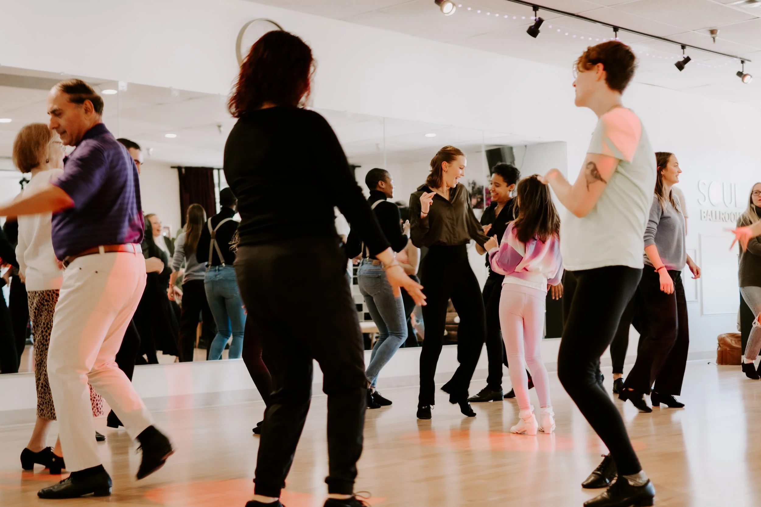 People dancing and socializing in a dance studio.