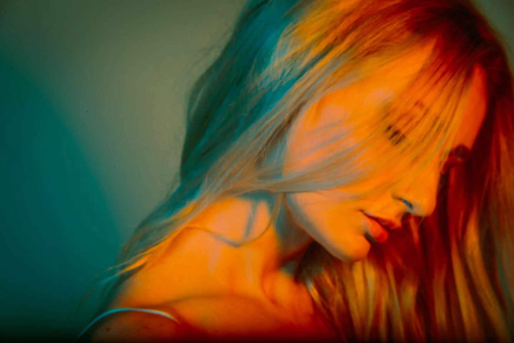 Close-up artistic portrait of a woman with colorful, flowing hair and a relaxed expression.