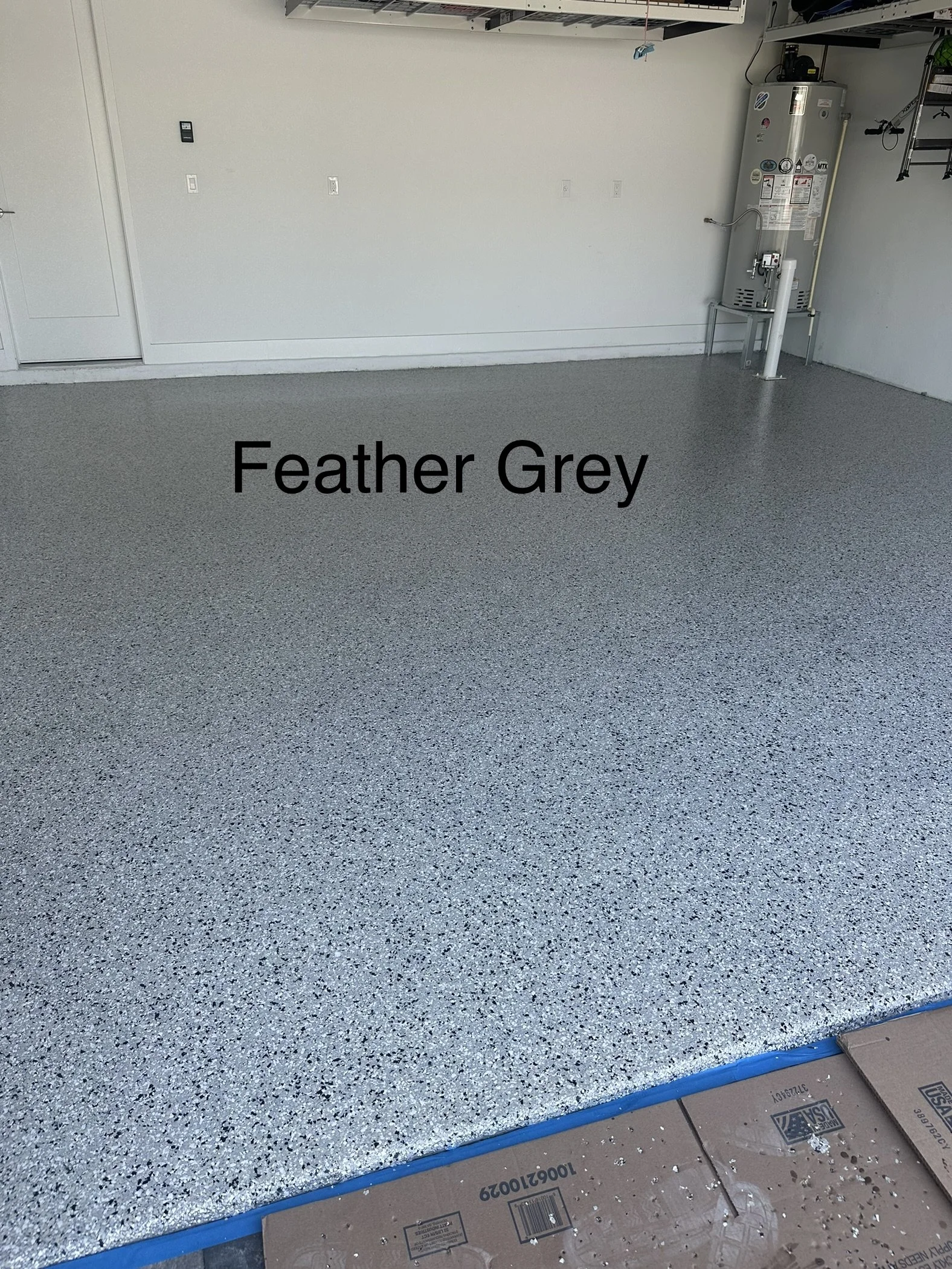 Garage with a speckled grey floor labeled 'Feather Grey' in black text, water heater on the wall, and various tools and supplies.