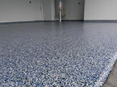 Close-up of a blue speckled epoxy floor in an indoor utility or maintenance room.