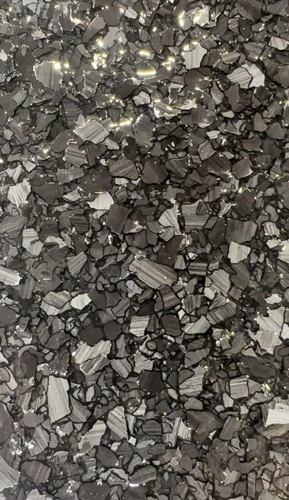 Close-up of black and gray gravel with shiny reflections.