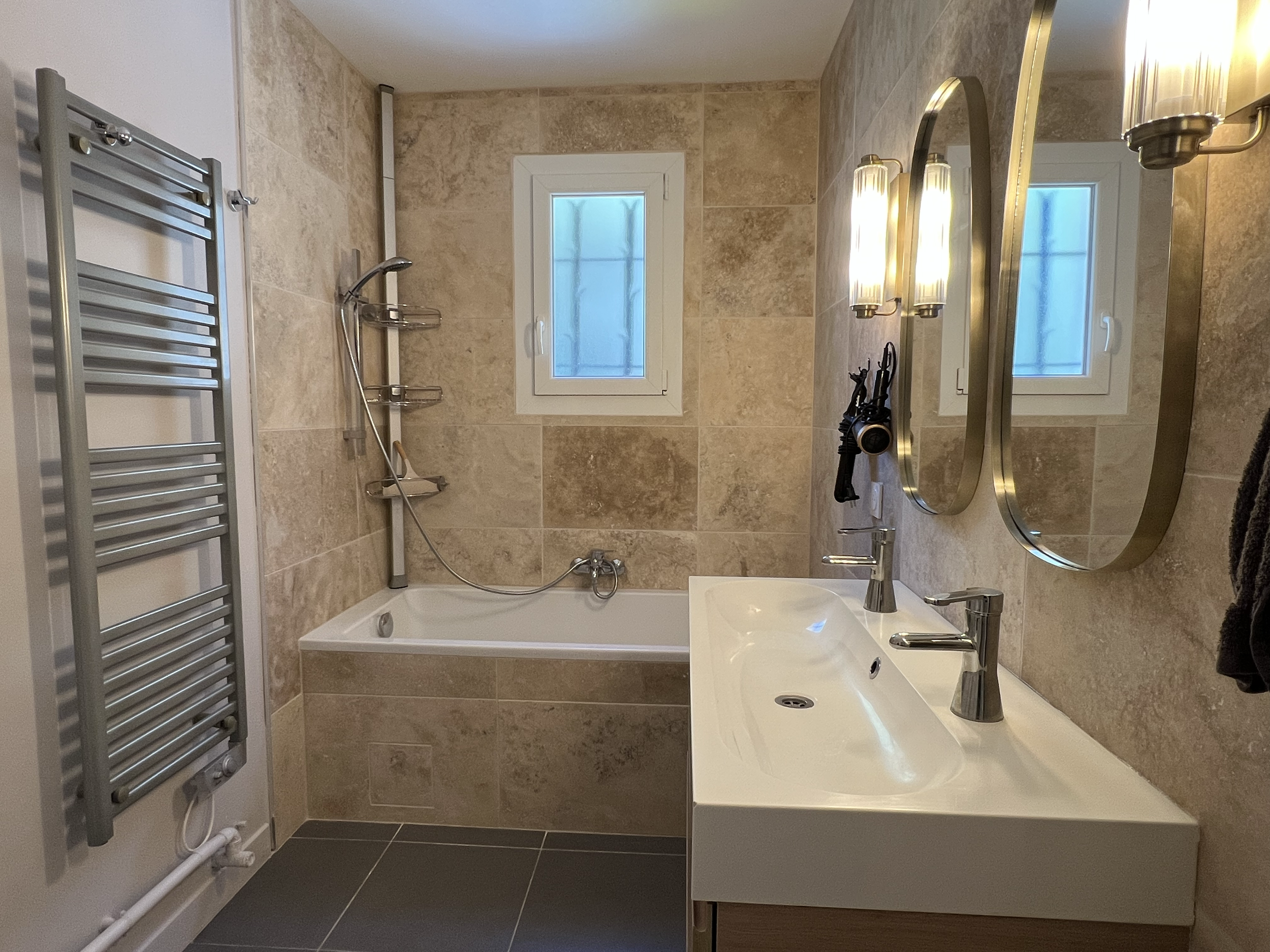Salle d’eau pratique avec double vasque, sèche serviettes et  baignoire pour un confort optimal