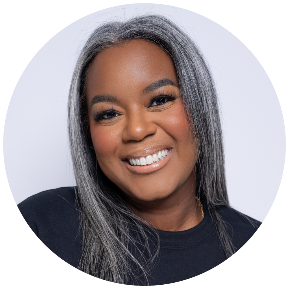 A woman with gray hair smiling in a black shirt against a white background.