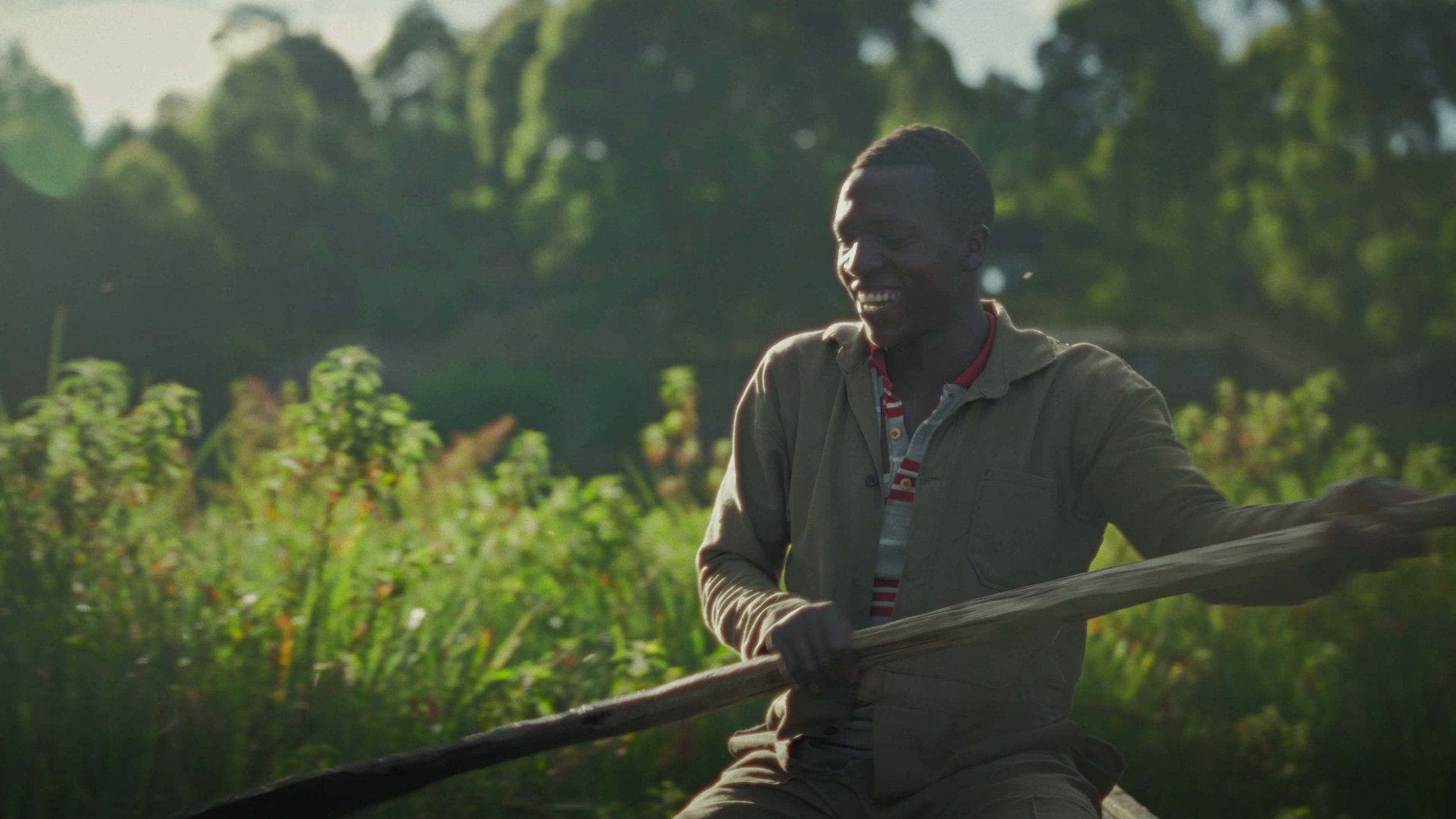 A man rowing a boat in small river streams of Rugezi Marsh