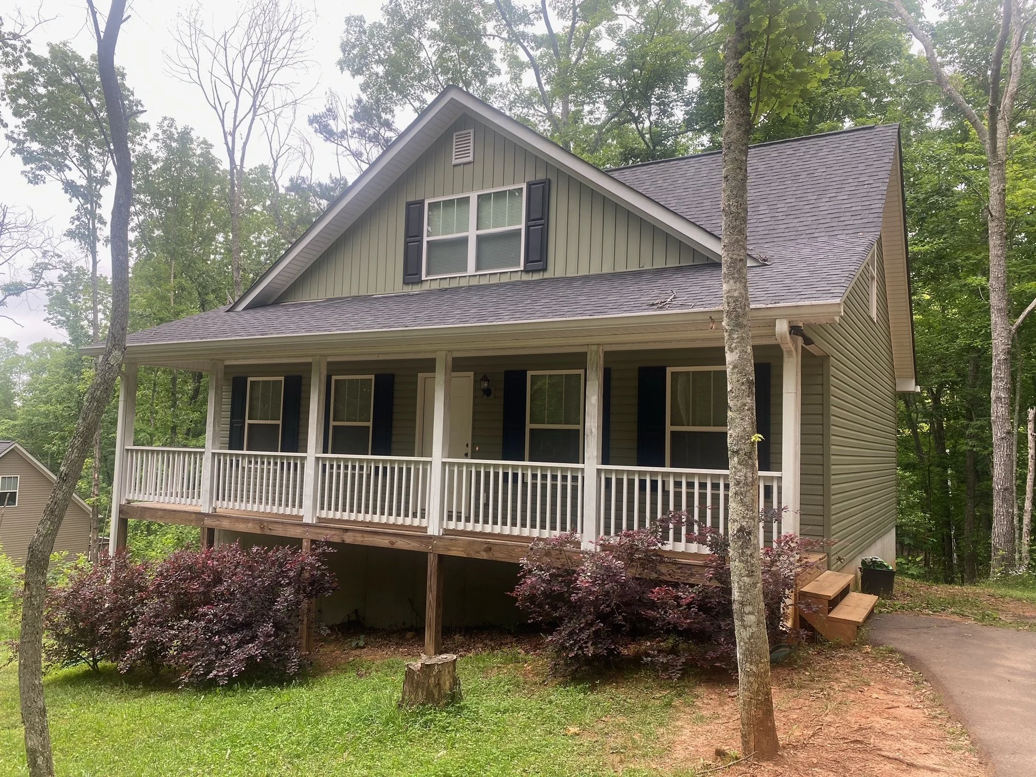 Ideal college or family rental near University of North Georgia and Dahlonega. The house is elevated with stairs leading to the porch. There are trees around and bushes in front of the house.
