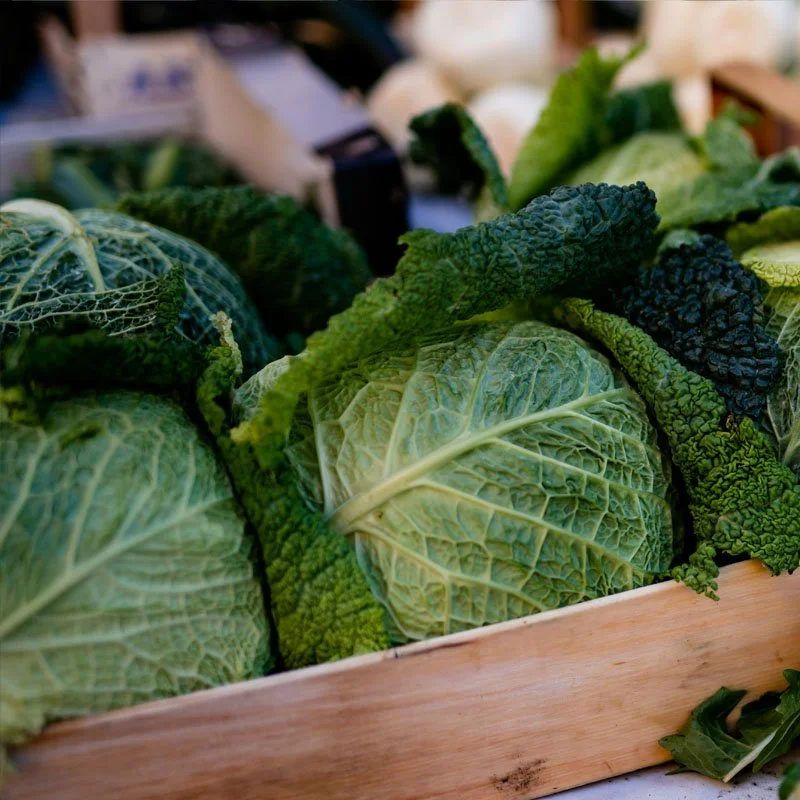 Fresh green cabbage and kale in a wooden crate at a market