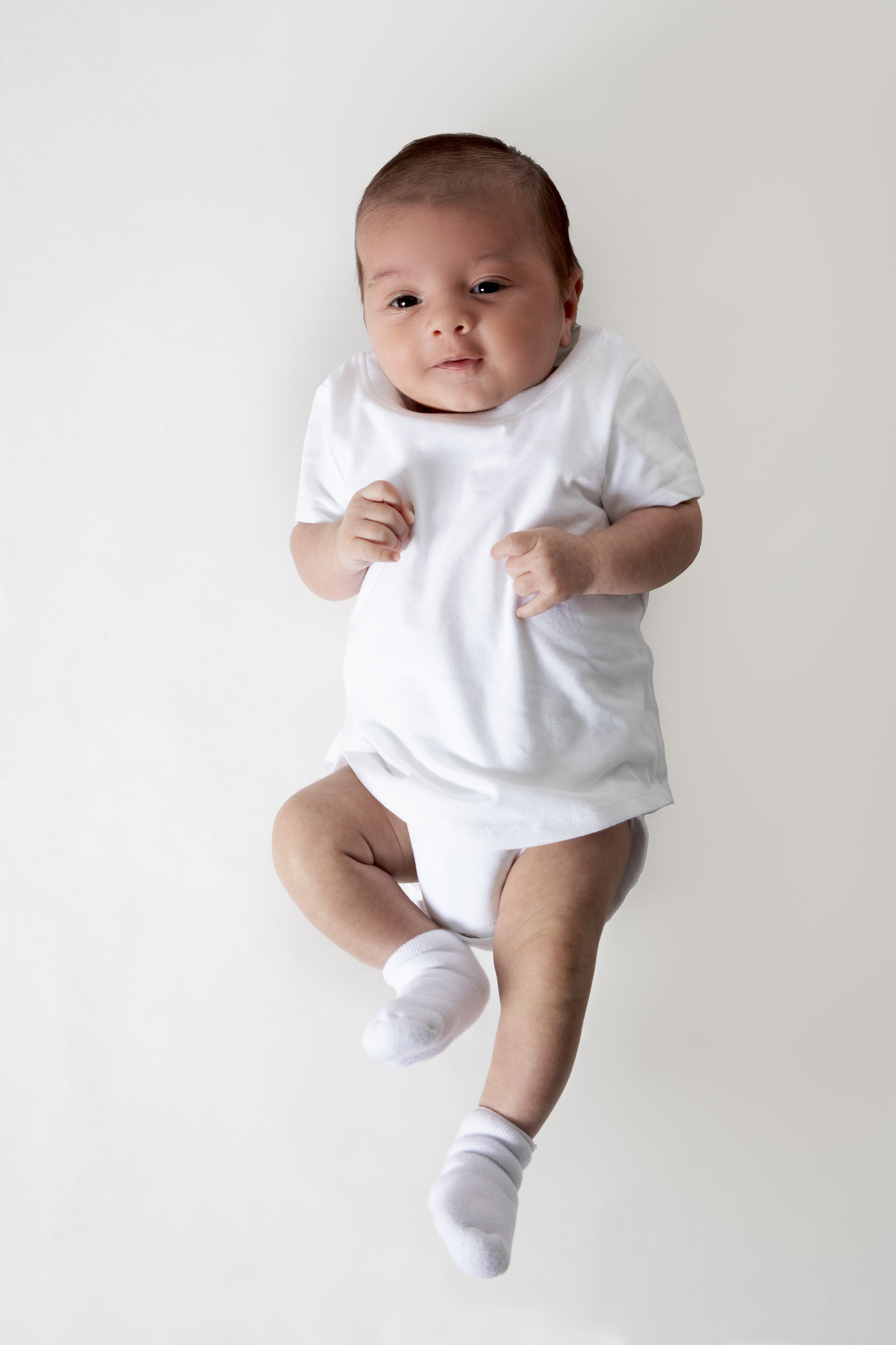 Newborn baby in white clothing lying on a light surface