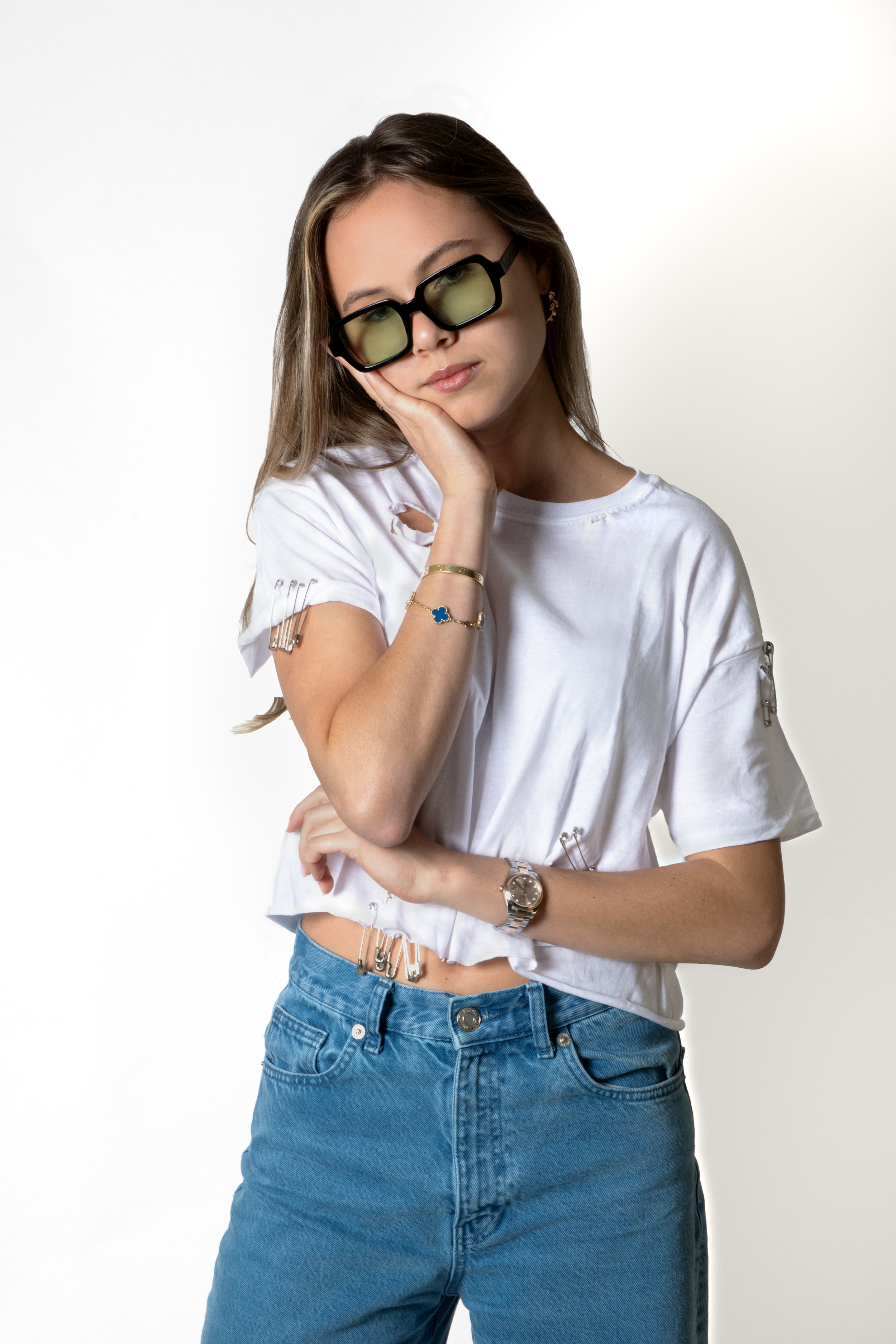 Woman wearing sunglasses, white crop top, and blue jeans