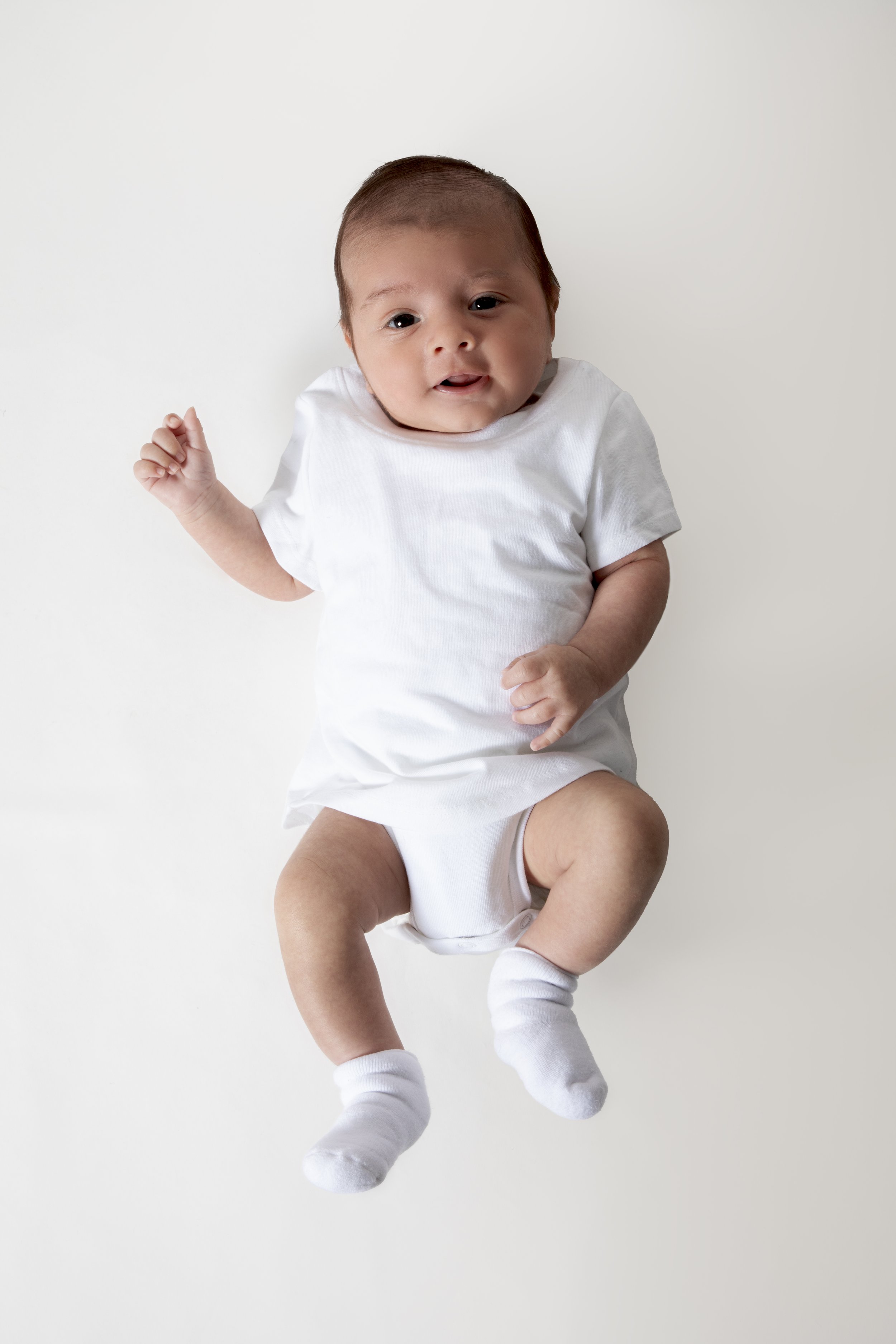 Smiling baby in white onesie and socks on white background