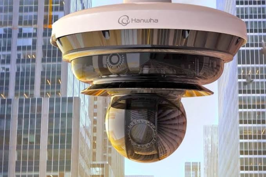 A Hanwha security camera with a dome shape mounted on a building in a cityscape.