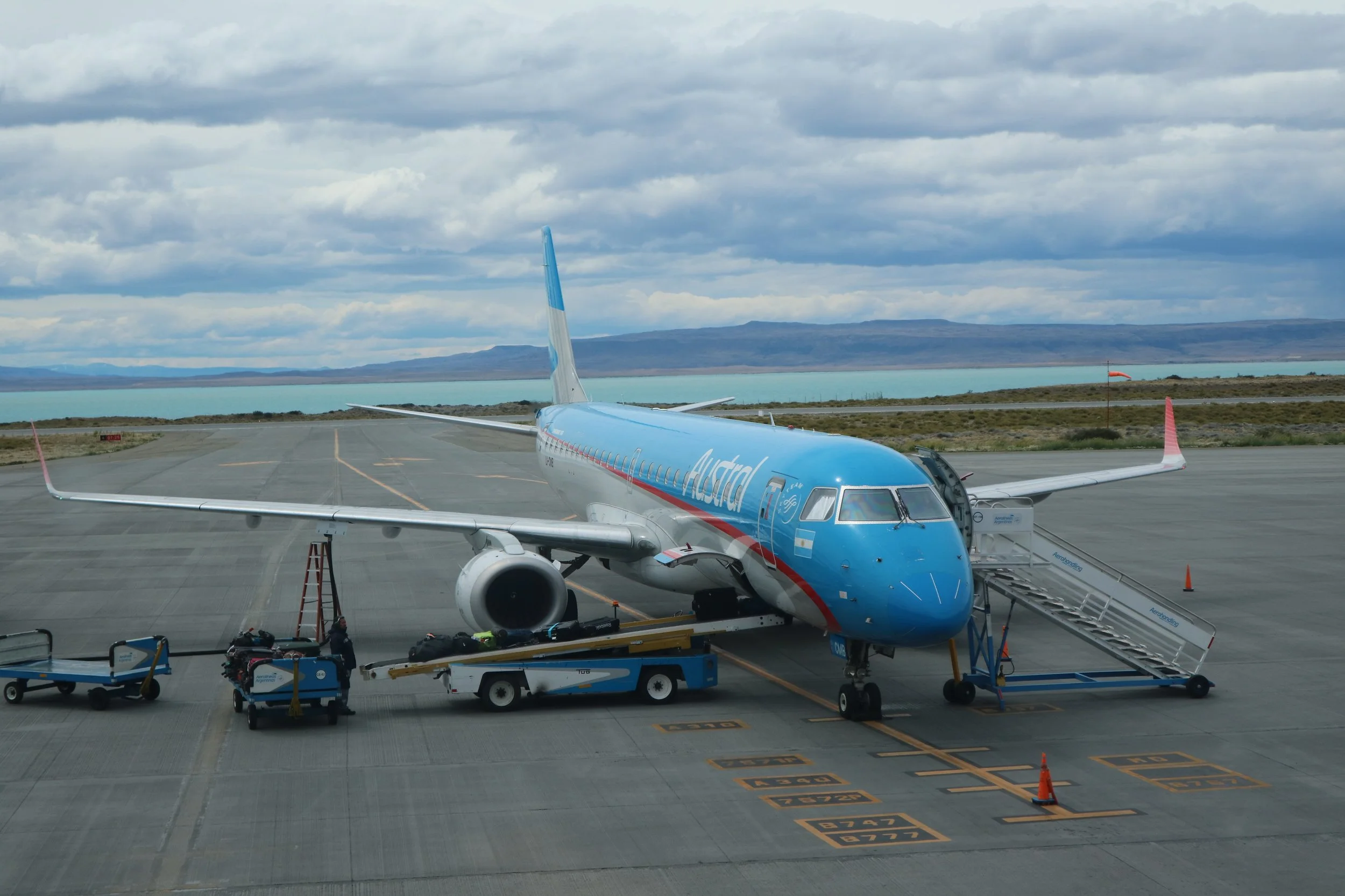Calafate Airport with an Astral Airlines plane on the tarmac under a partly cloudy sky