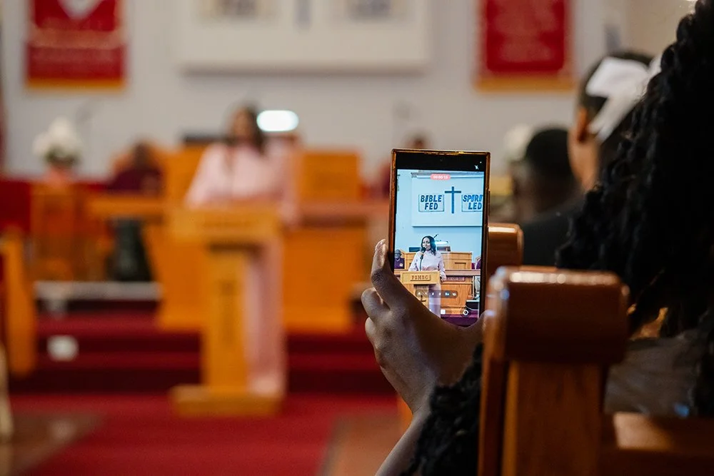 A churchgoer taking video of the testimonial by Shamyra Lavigne of Rise St. James