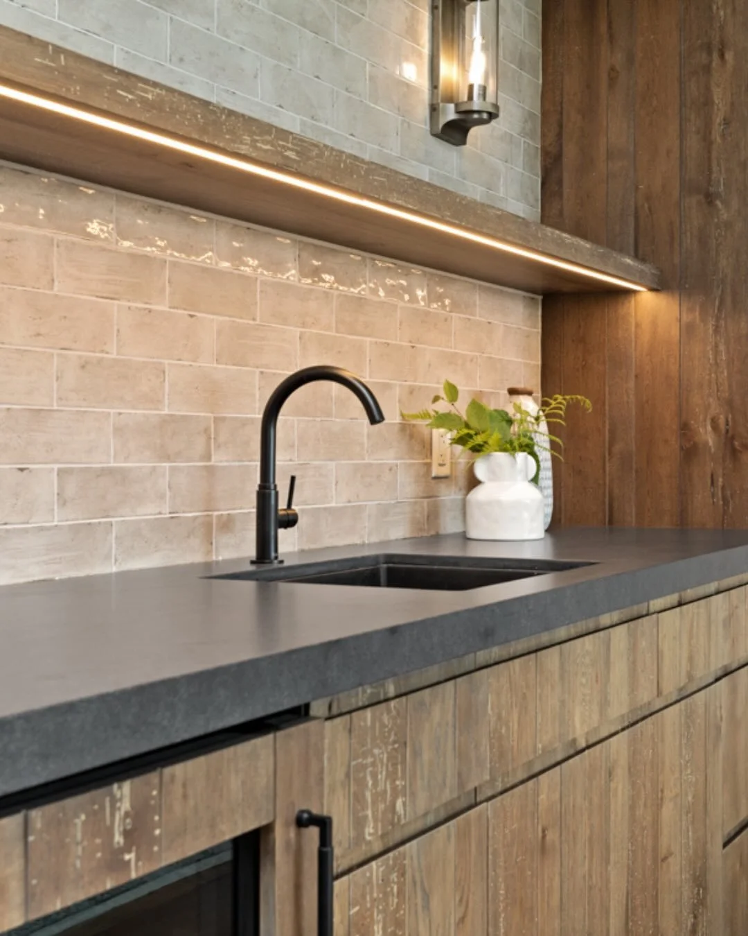Our Roberts Bay Cottage basement bar is the perfect place to end a busy day. ⁠
⁠
We chose reclaimed, weathered oak panels for a rustic, lived-in look, offset by iridescent backsplash tiling and @silestonebycosentino countertops. The bar features a bu