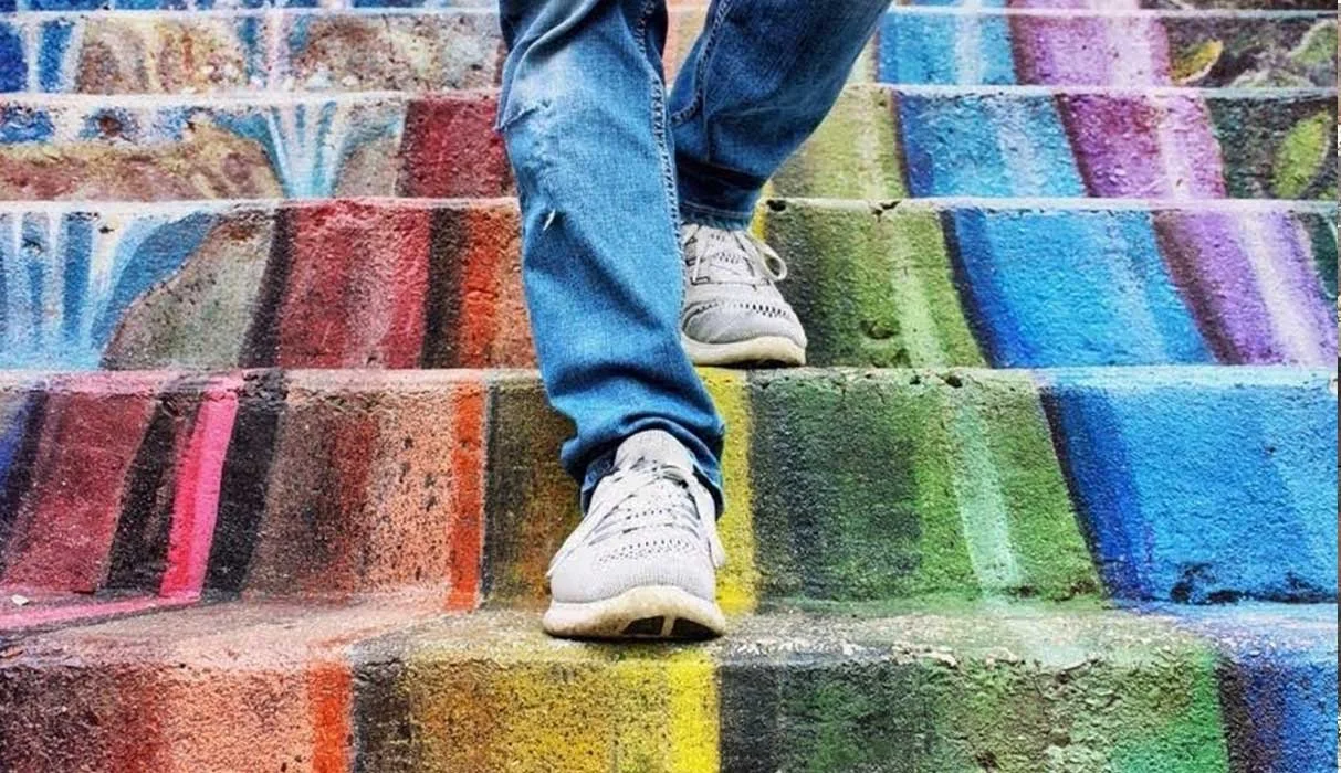 Person walking down rainbow colored stairs