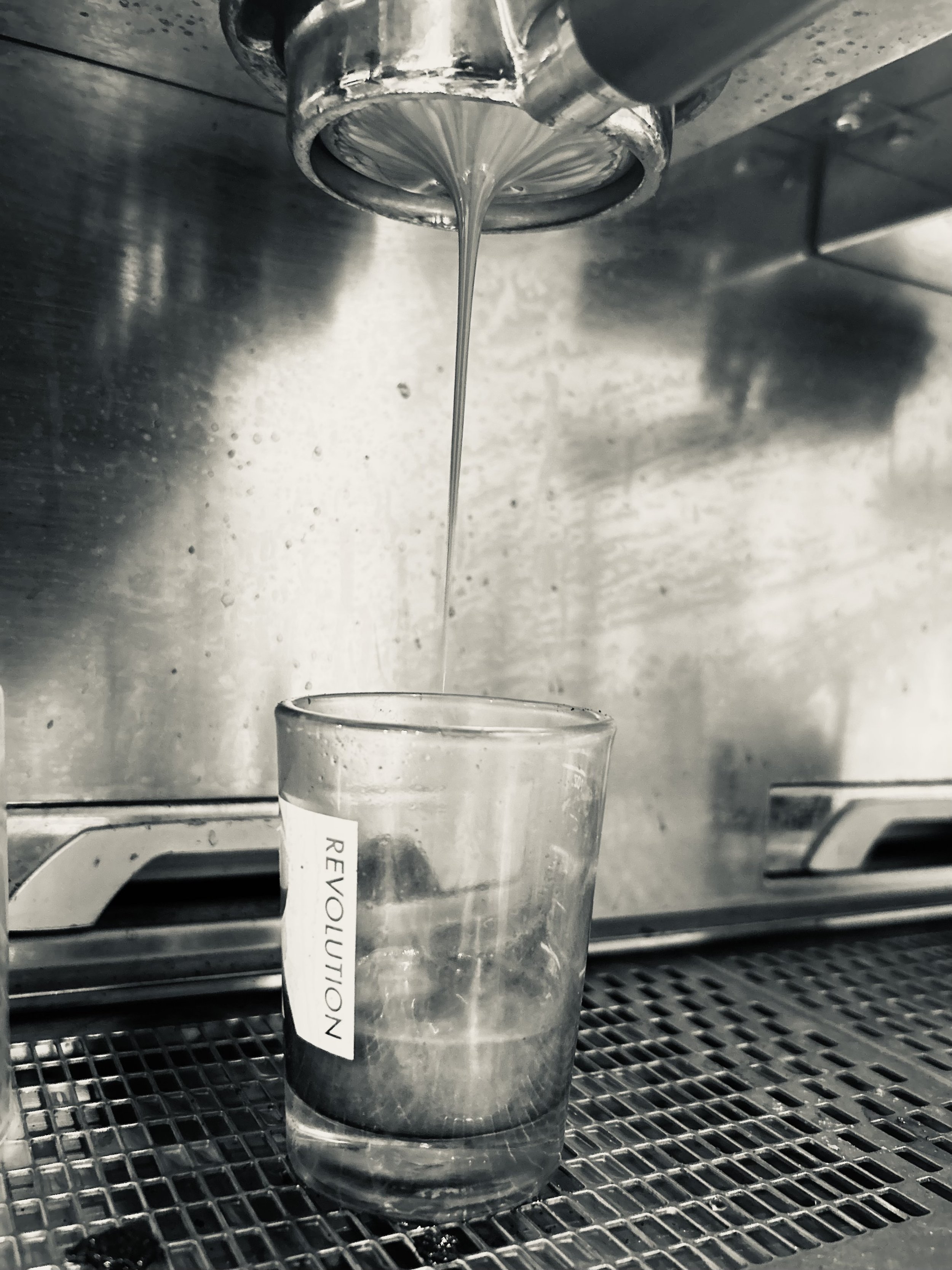 A glass being filled with water from a tap in a stainless steel sink with a scratchy metal surface.