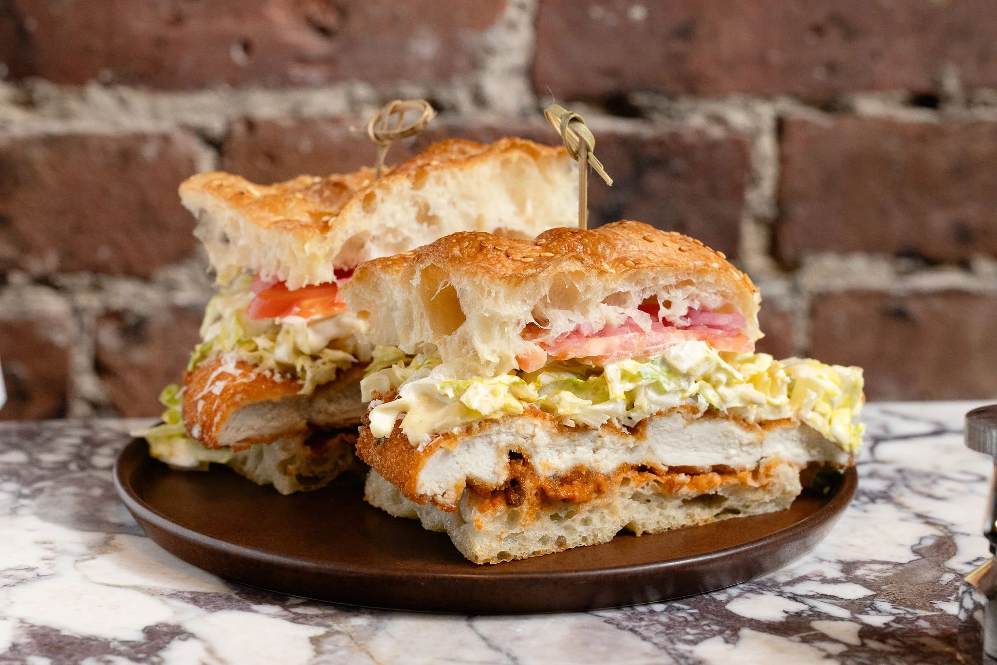 A chicken casear sandwich on sesame focaccia on a plate