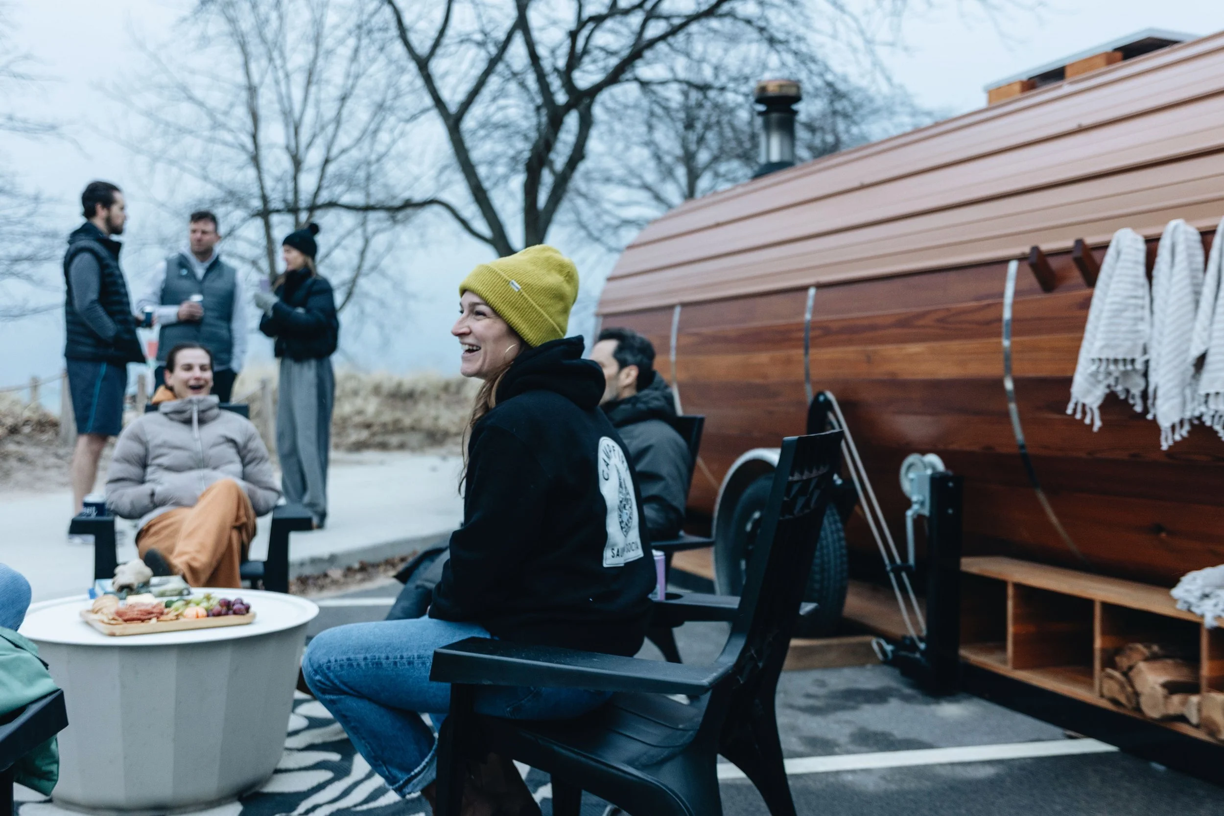 Silhouetted group of people around a beach bonfire at sunset.