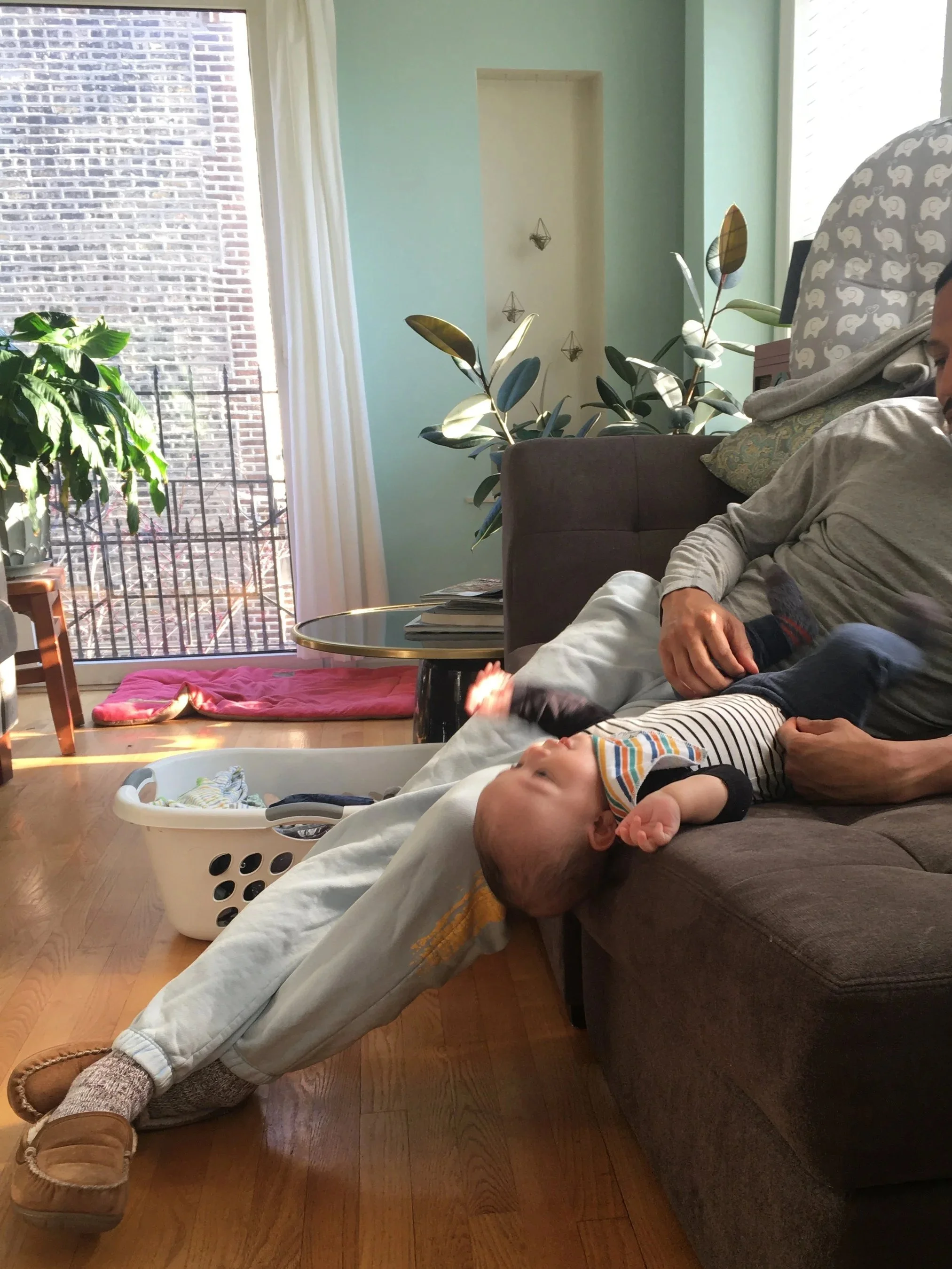 New dad with baby and laundry, showing mental load of parenthood therapy can address