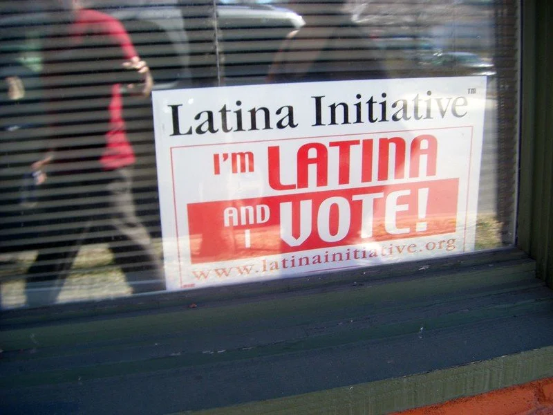 Sign on window with text 'Latina Initiative I'm Latina and I Vote!' promoting voter participation