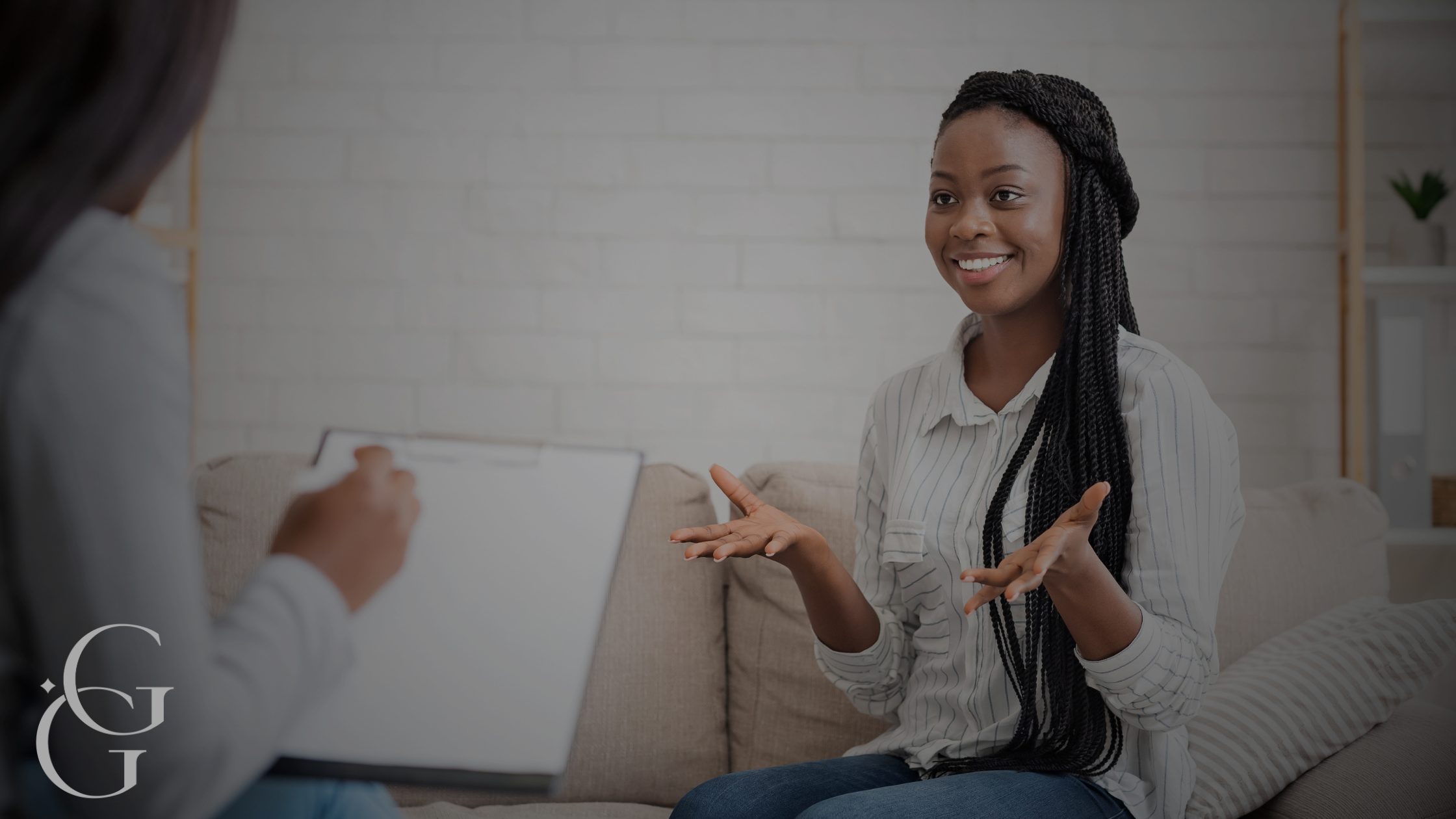 A woman smiling during a therapy or counseling session with a therapist taking notes.