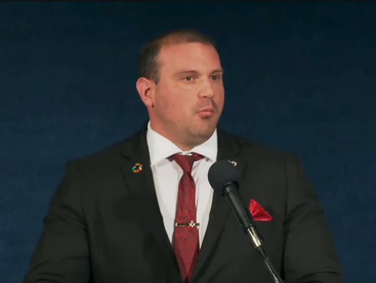 A man in a suit speaking at a microphone.