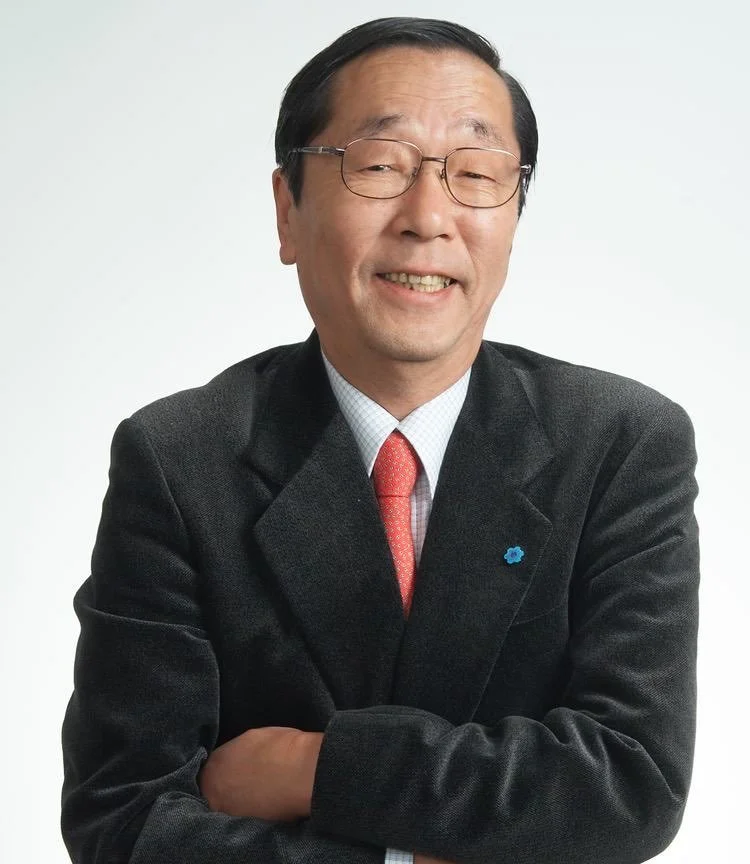 smiling man in a suit with red tie and glasses, arms crossed
