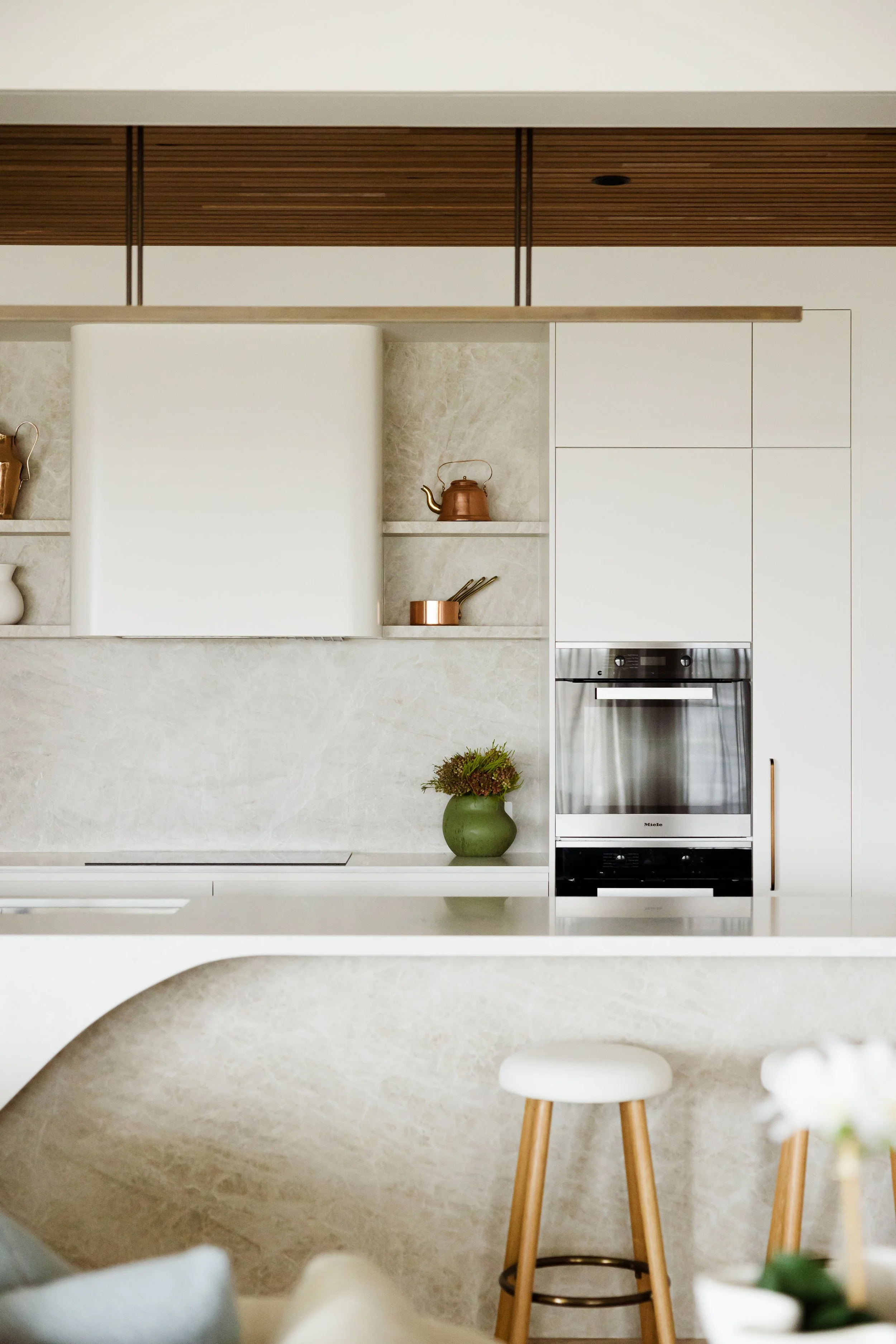 Luxury Freshwater kitchen renovation featuring a Taj Mahal quartzite island with curved end detail, custom rangehood, floating stone shelves and bespoke white joinery.