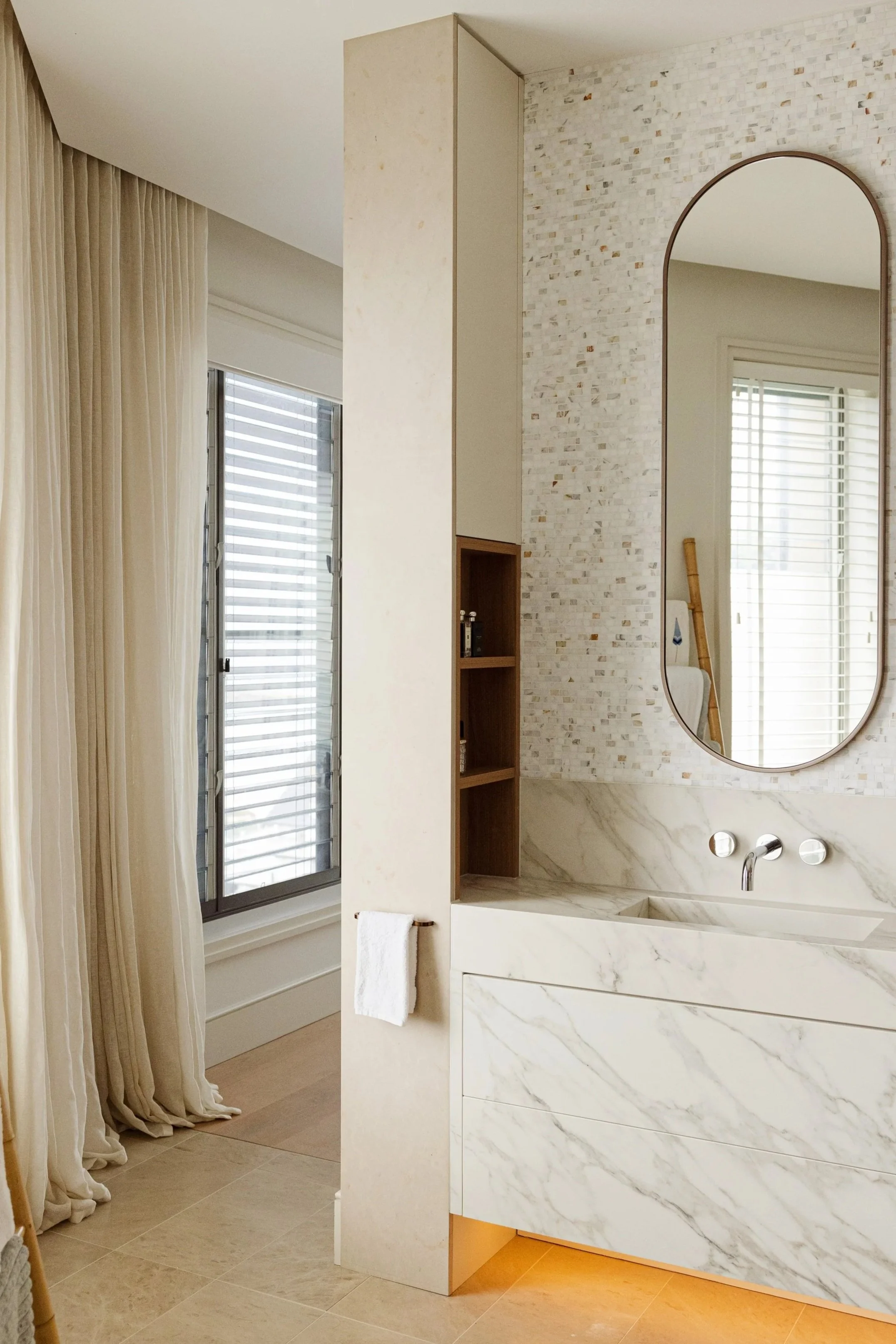 Bespoke bathroom vanity with natural stone, custom cabinetry, feature mosaic tiles and curved mirror in Freshwater.