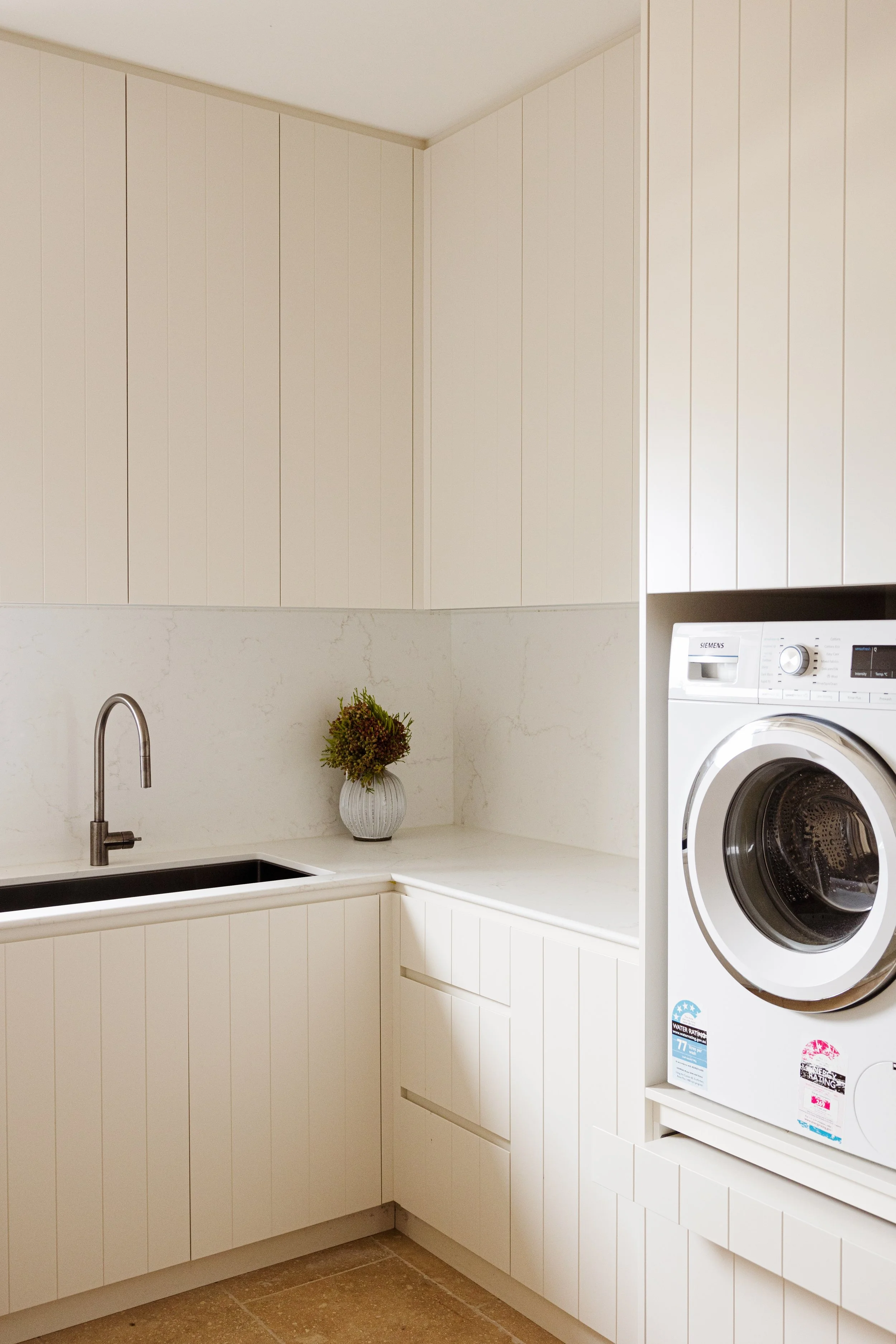 Luxury laundry joinery featuring custom V-groove cabinetry, engineered stone benchtops and practical built-in storage.