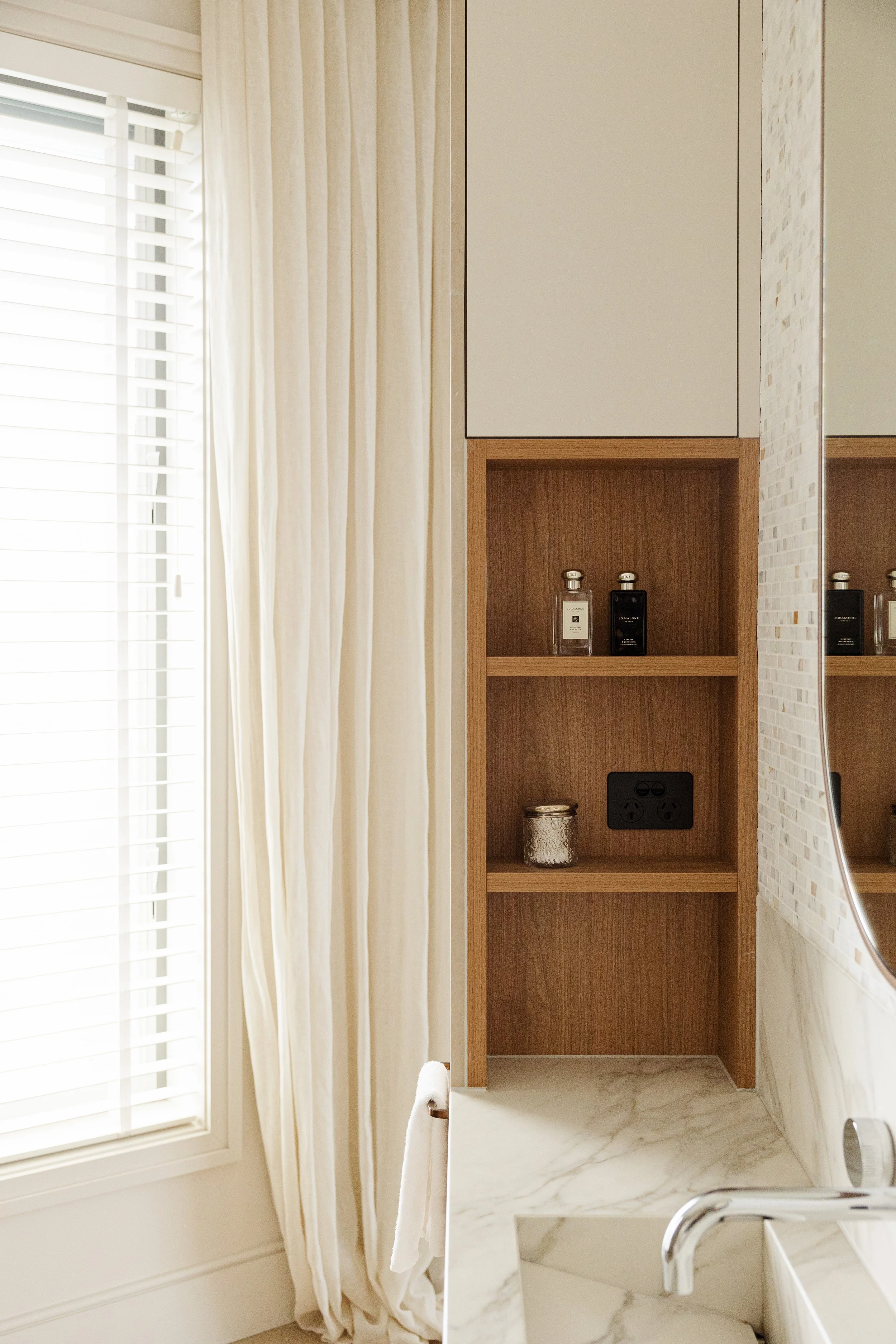 Luxury ensuite vanity featuring custom joinery, marble-look stone, mosaic feature wall and integrated open shelving.