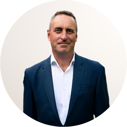 Headshot of a middle-aged man in a blue suit and white shirt, standing in front of a plain background.