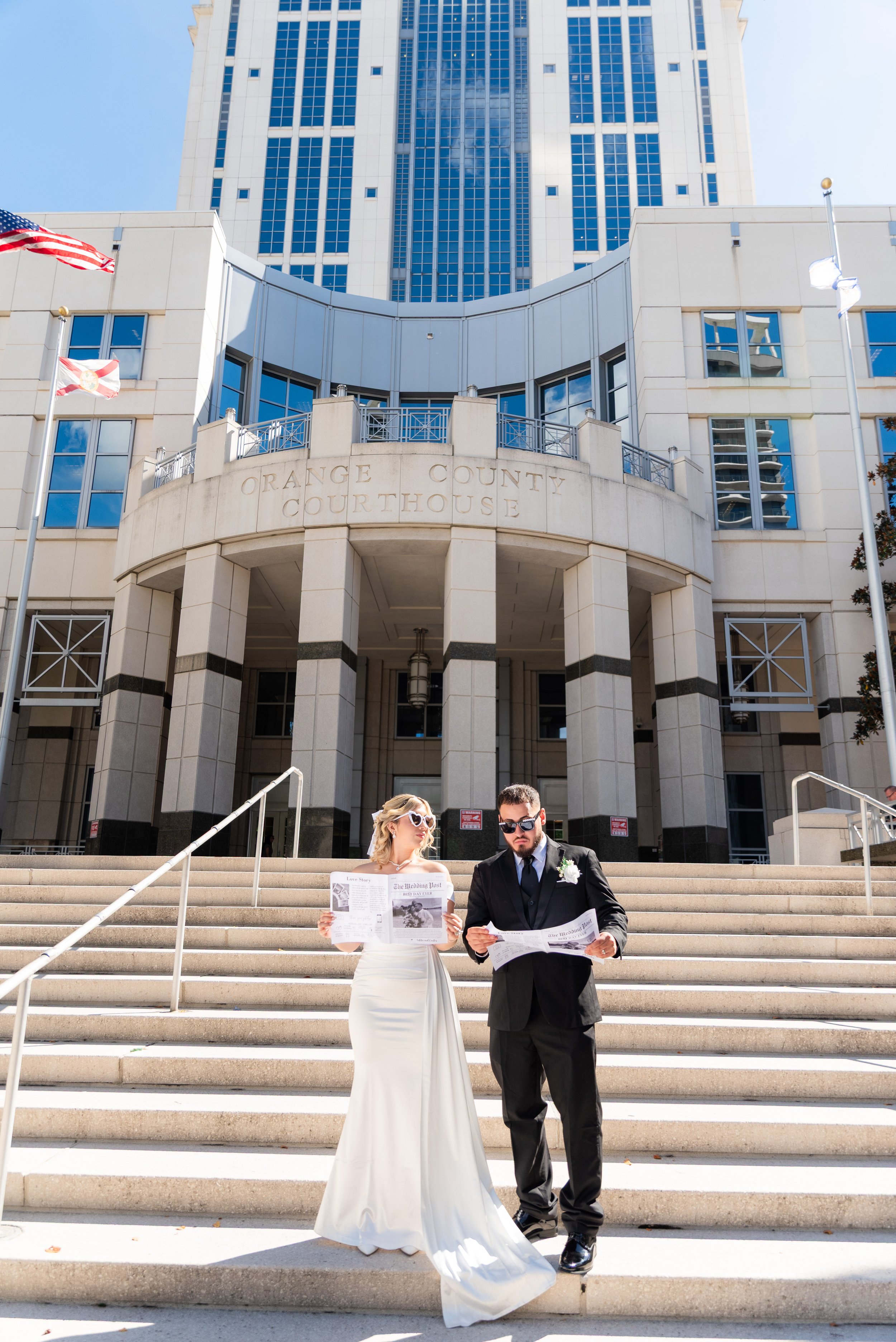 Bride and groom reading newspapers on the steps of the Orange County Courthouse.
