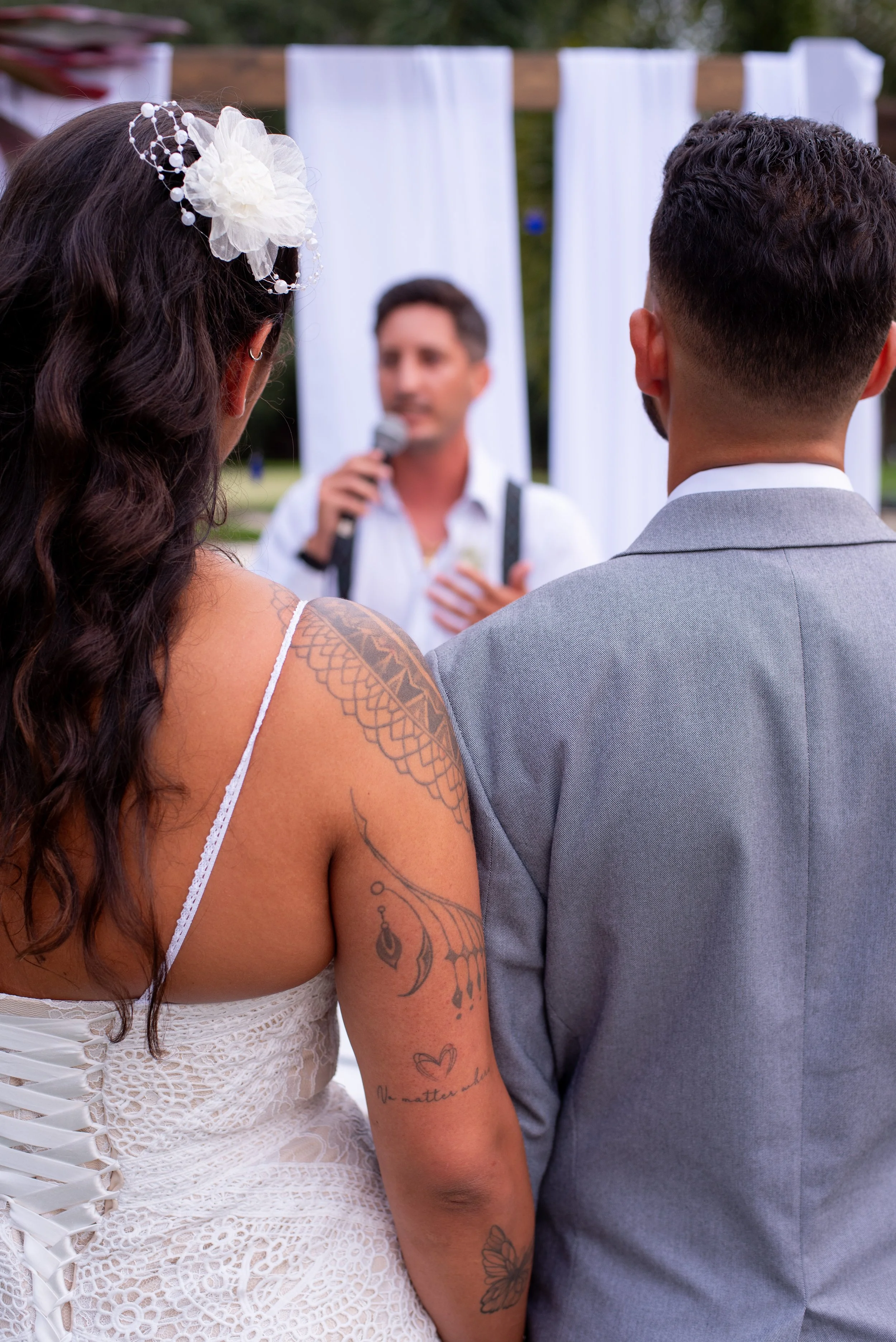 Bride and groom standing together during wedding ceremony with officiant speaking in background.