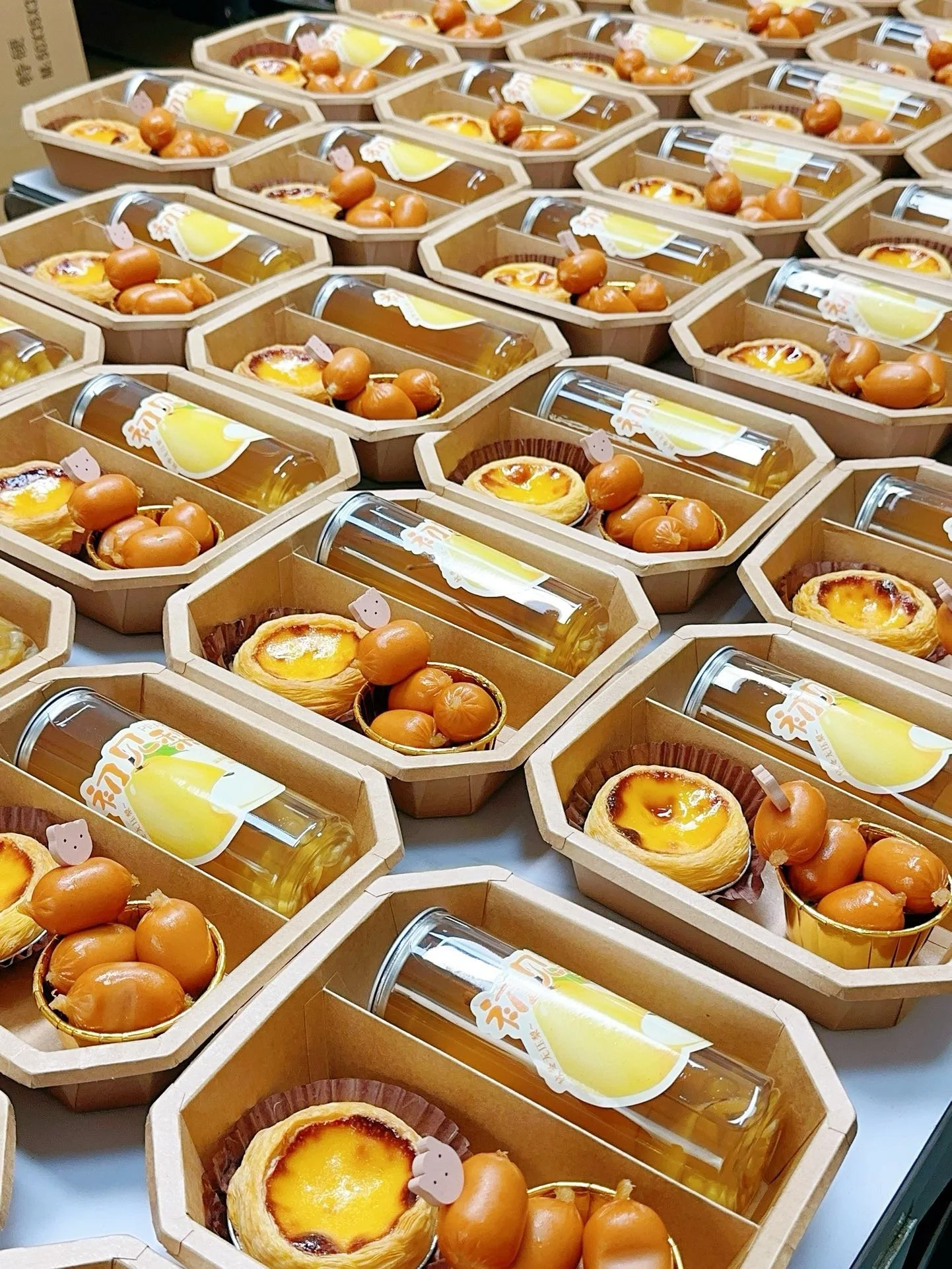 Multiple small gift boxes containing caramel candies and egg tarts, decorated with small pink pig-shaped toppers.