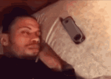Person lying on bed with a smartphone nearby on a pillow waiting for a phone call.