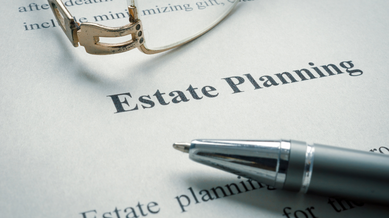 Close-up of a document titled 'Estate Planning' with a silver pen and a pair of glasses placed on top of it.