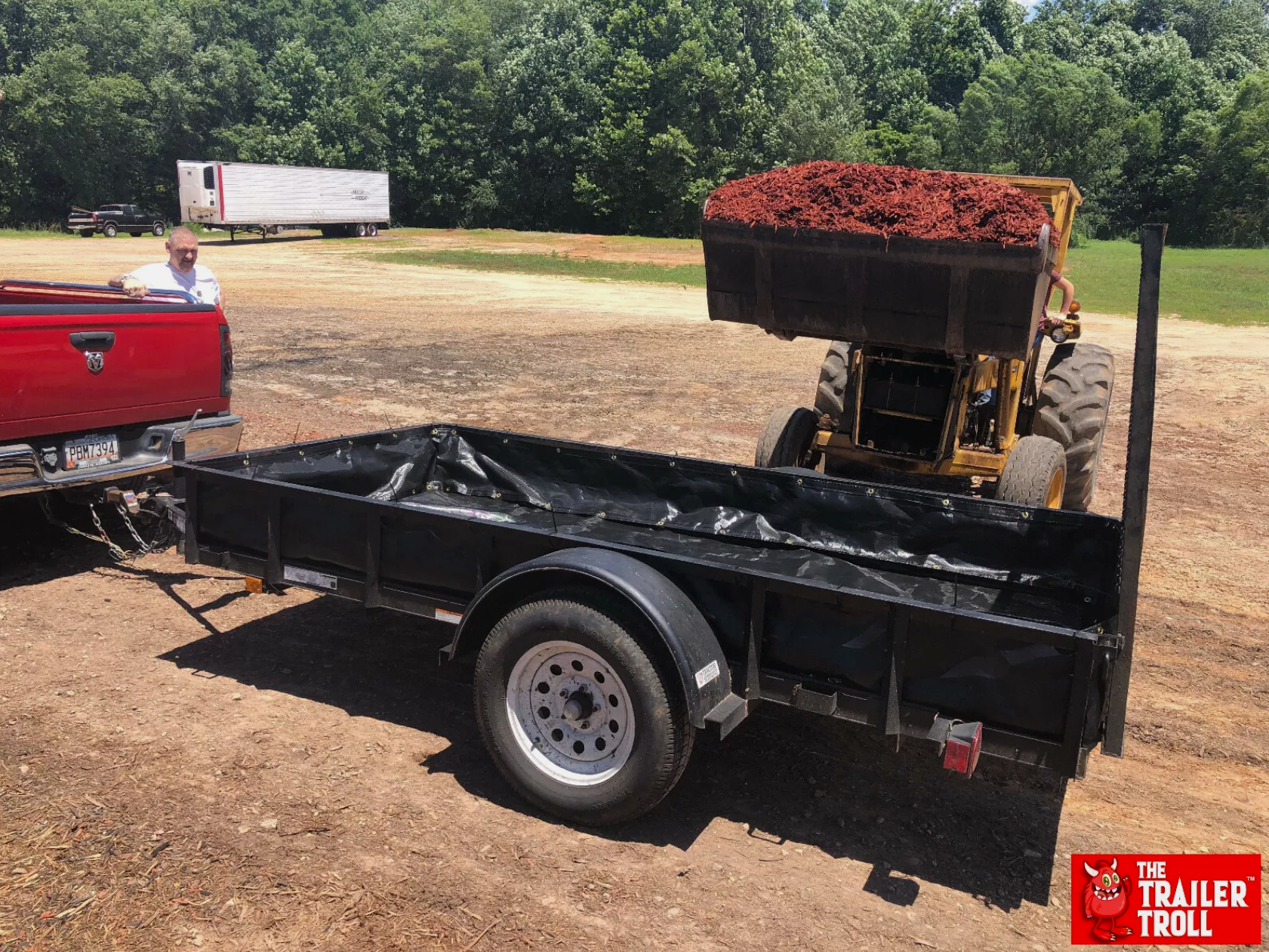 Loading mulch into a utility trailer using a front loader for easy transport and delivery.
