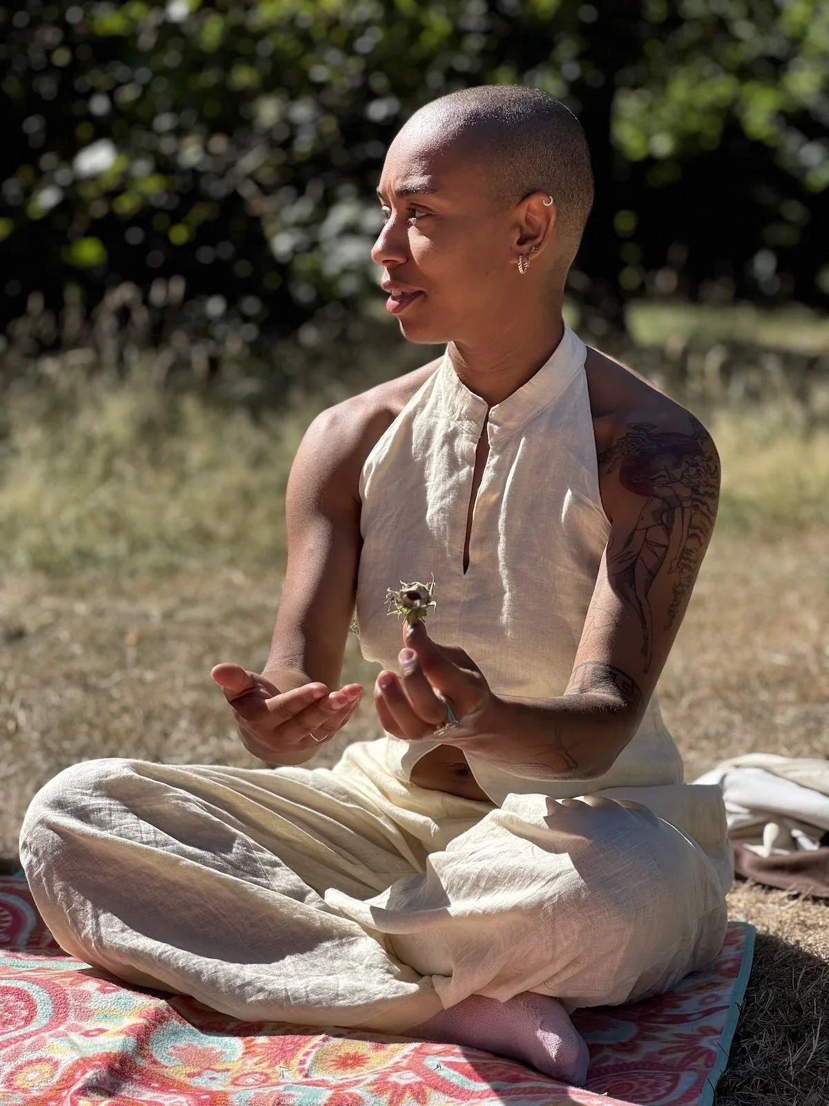 Ilayda Bakare sits cross legged in the grass discussing a found natural object