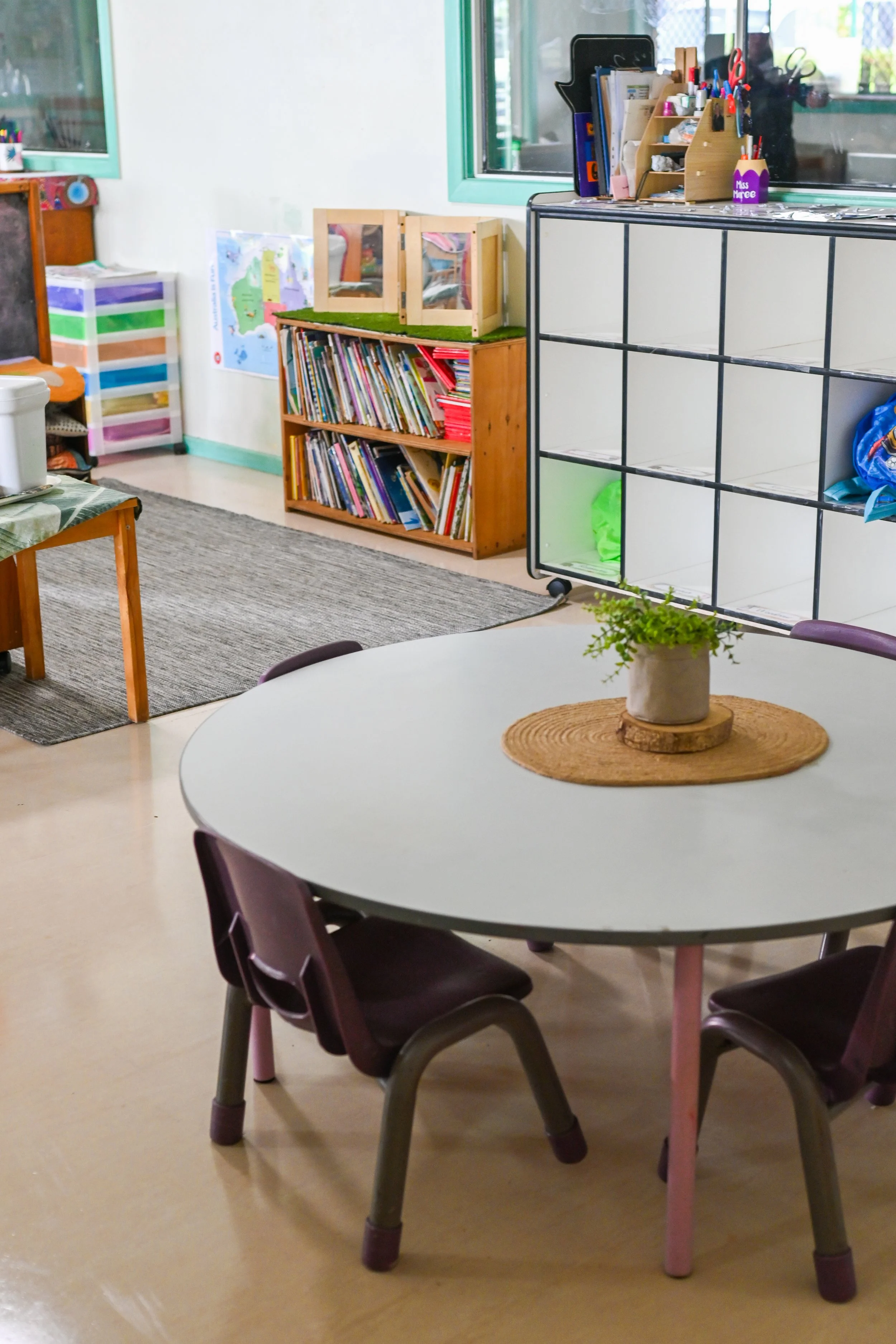 Classroom with a round table, small chairs, bookshelves, and storage cubes.