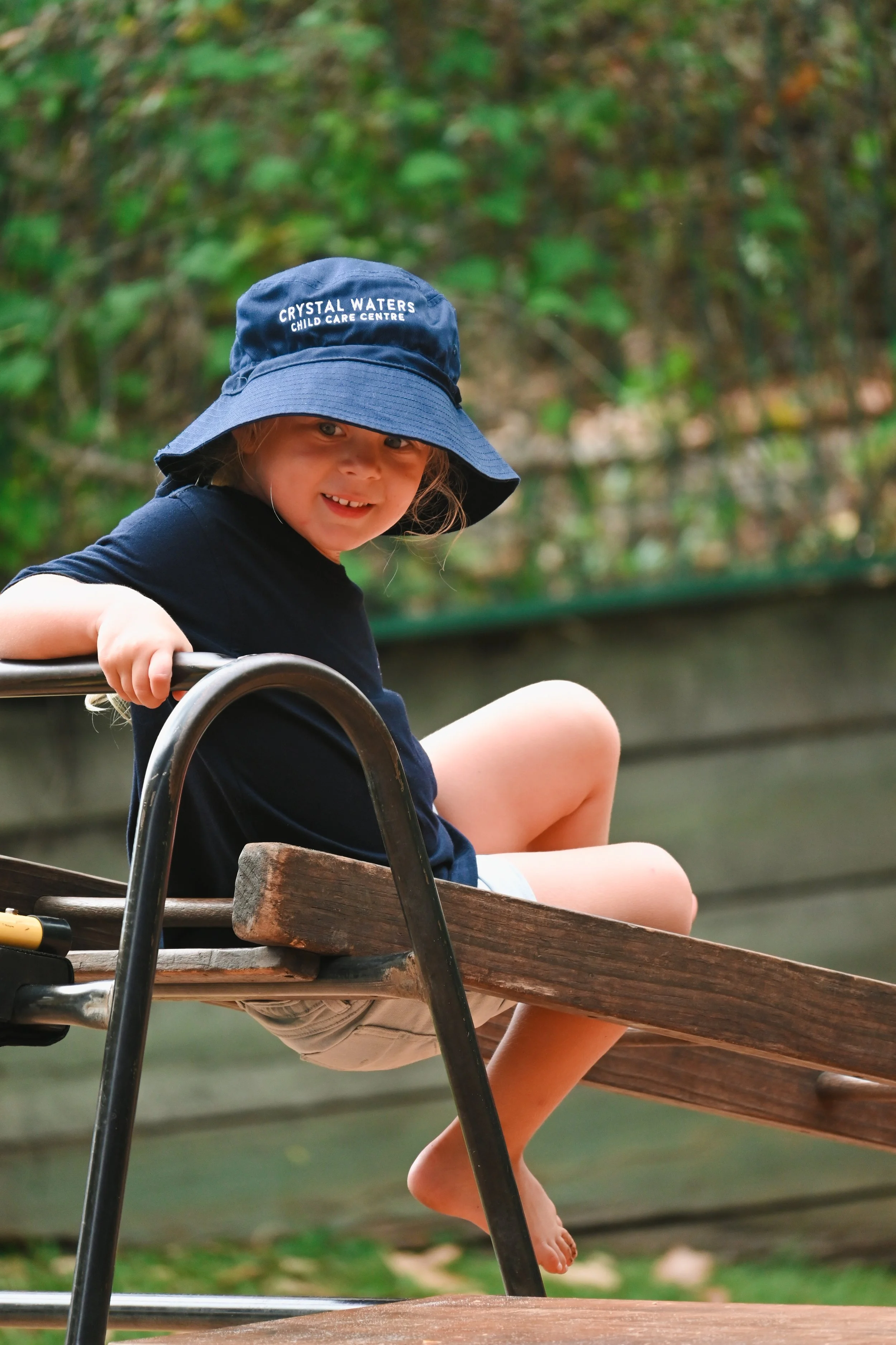 Child on a wooden seesaw wearing a blue hat