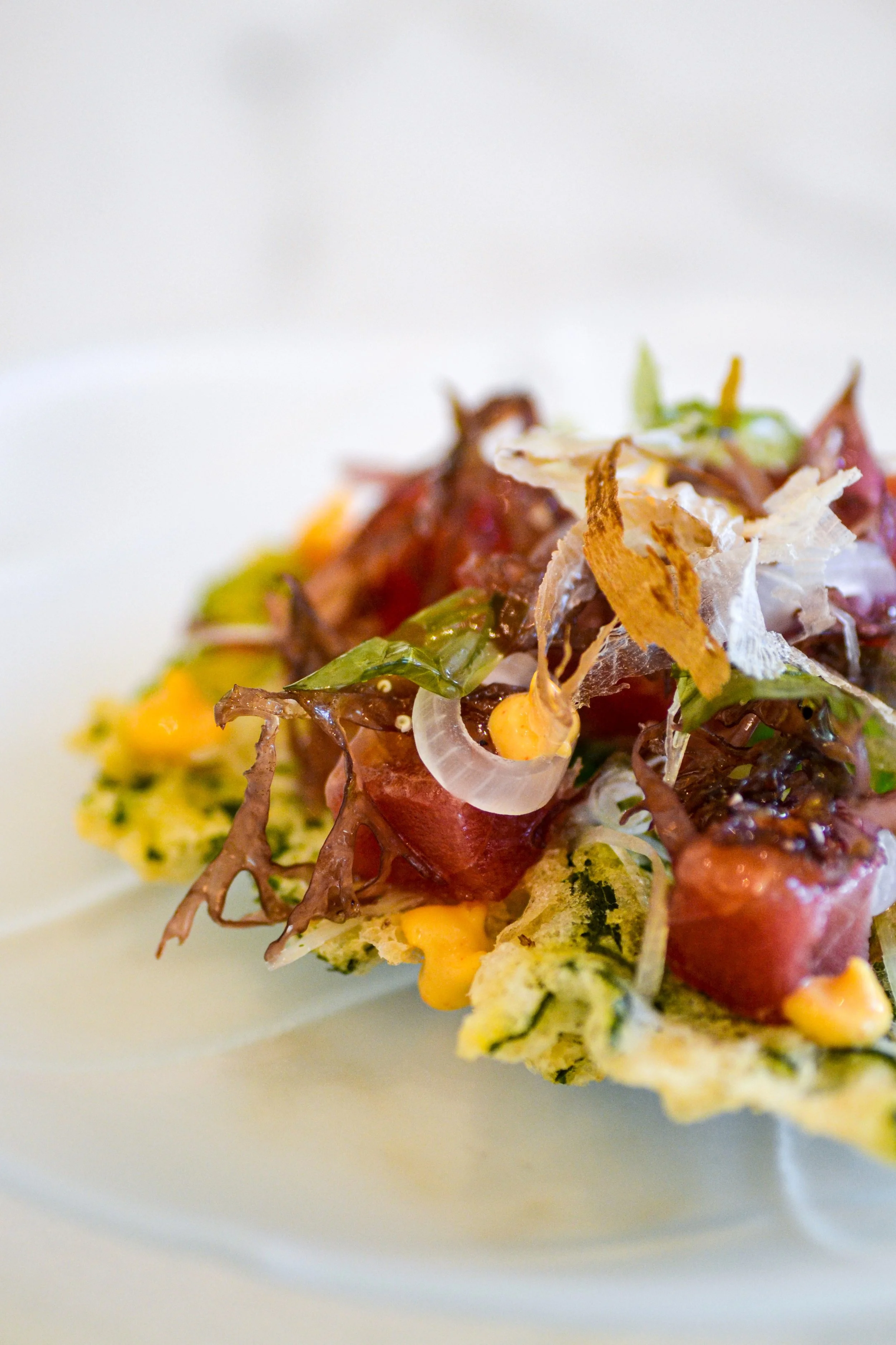 Tuna tartare with yellowfin diced over tempura shiso leaf — refined gourmet entrée by Chris Quirós, highlighting Japanese technique and vibrant plating.