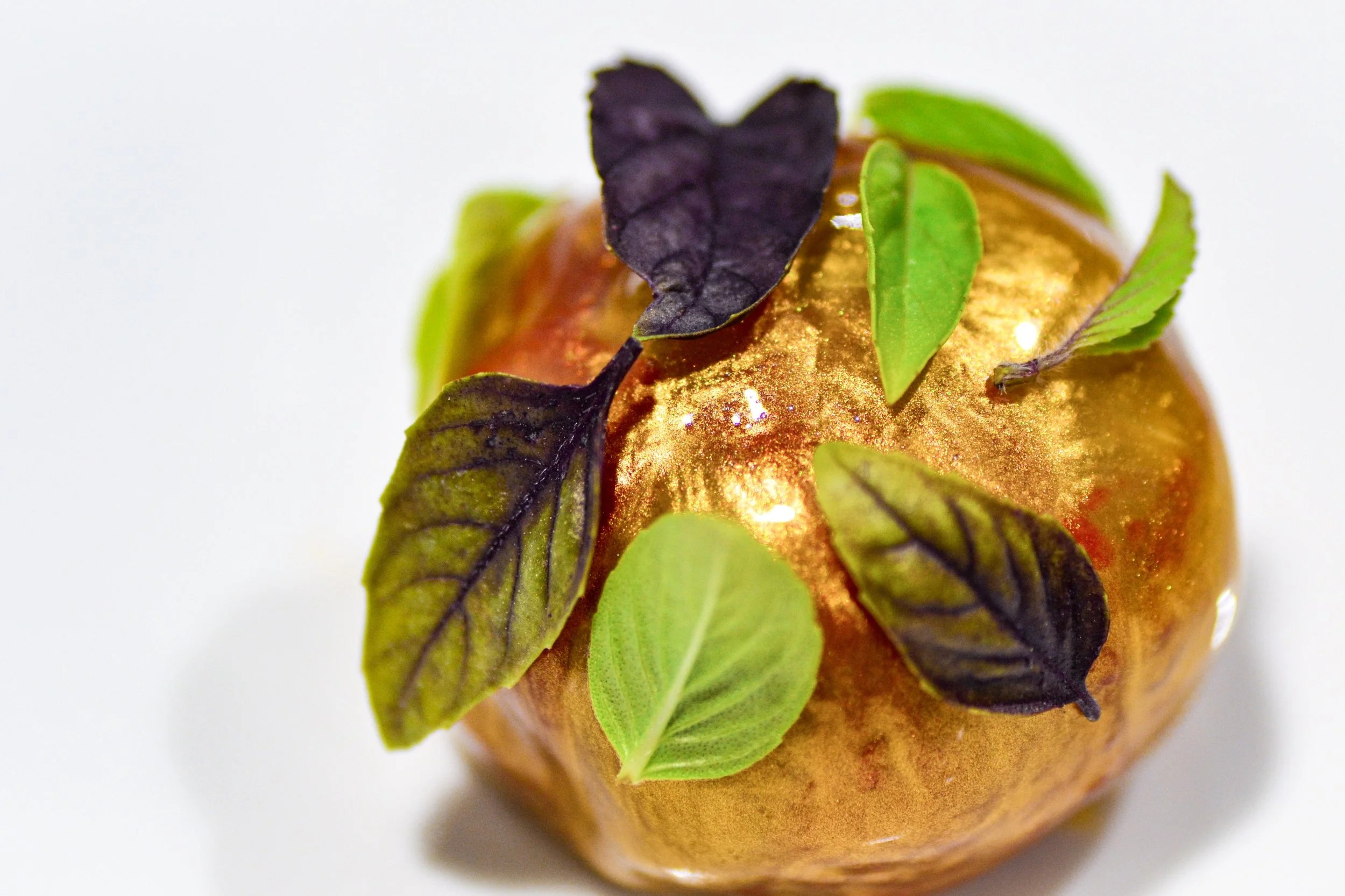 Golden tomato filled with basil pesto foam — a modern caprese reinterpretation by Chris Quirós, playing with colour, temperature, and Mediterranean flavour balance.