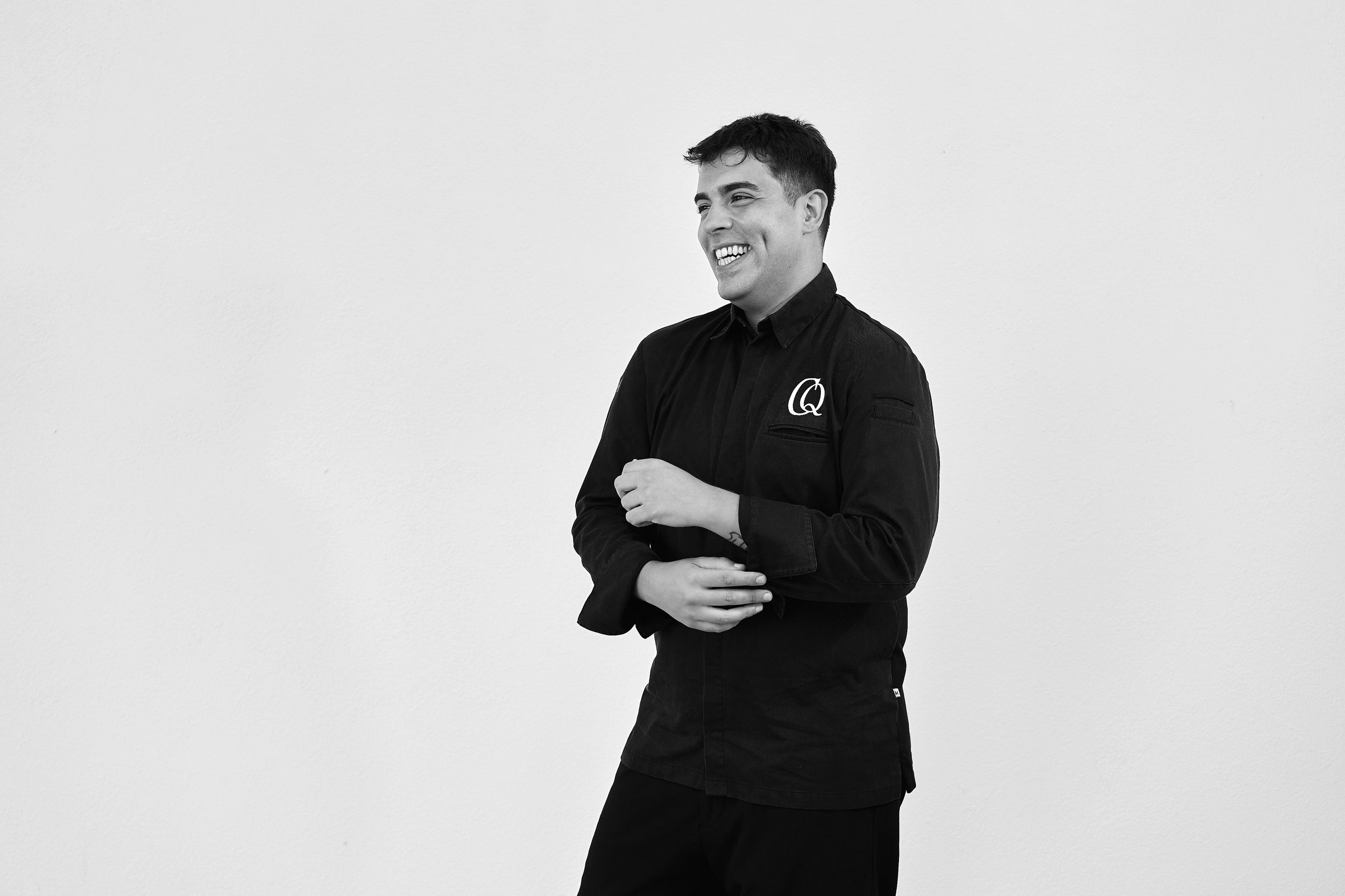 Professional portrait of Chris Quirós in chef uniform with CQ logo — culinary consultant and private chef, shot on plain background for brand identity.
